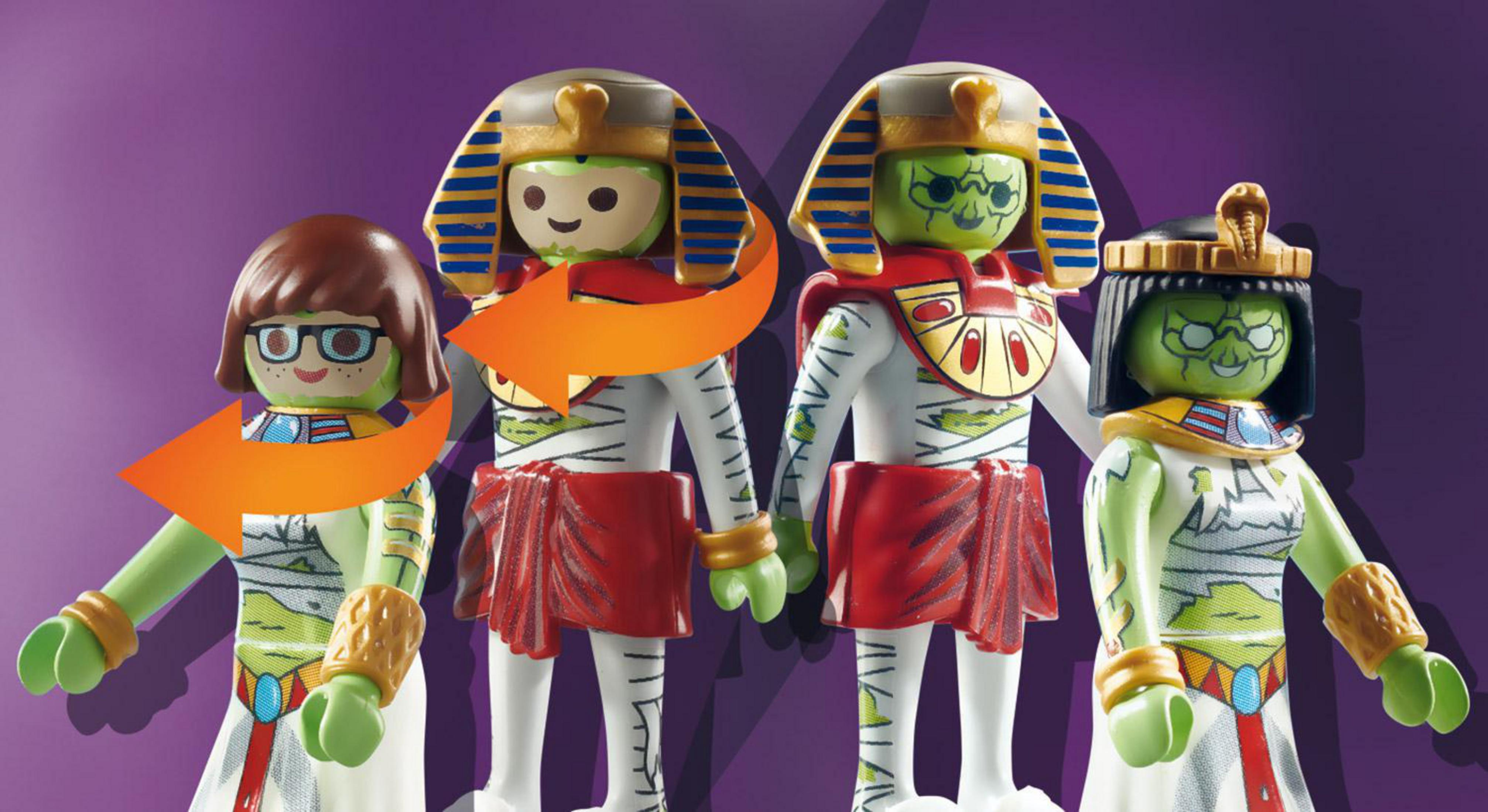 Vier Playmobil-Mumien, zwei einander zugewandt, mit Pfeil, der Verwandlung zeigt.