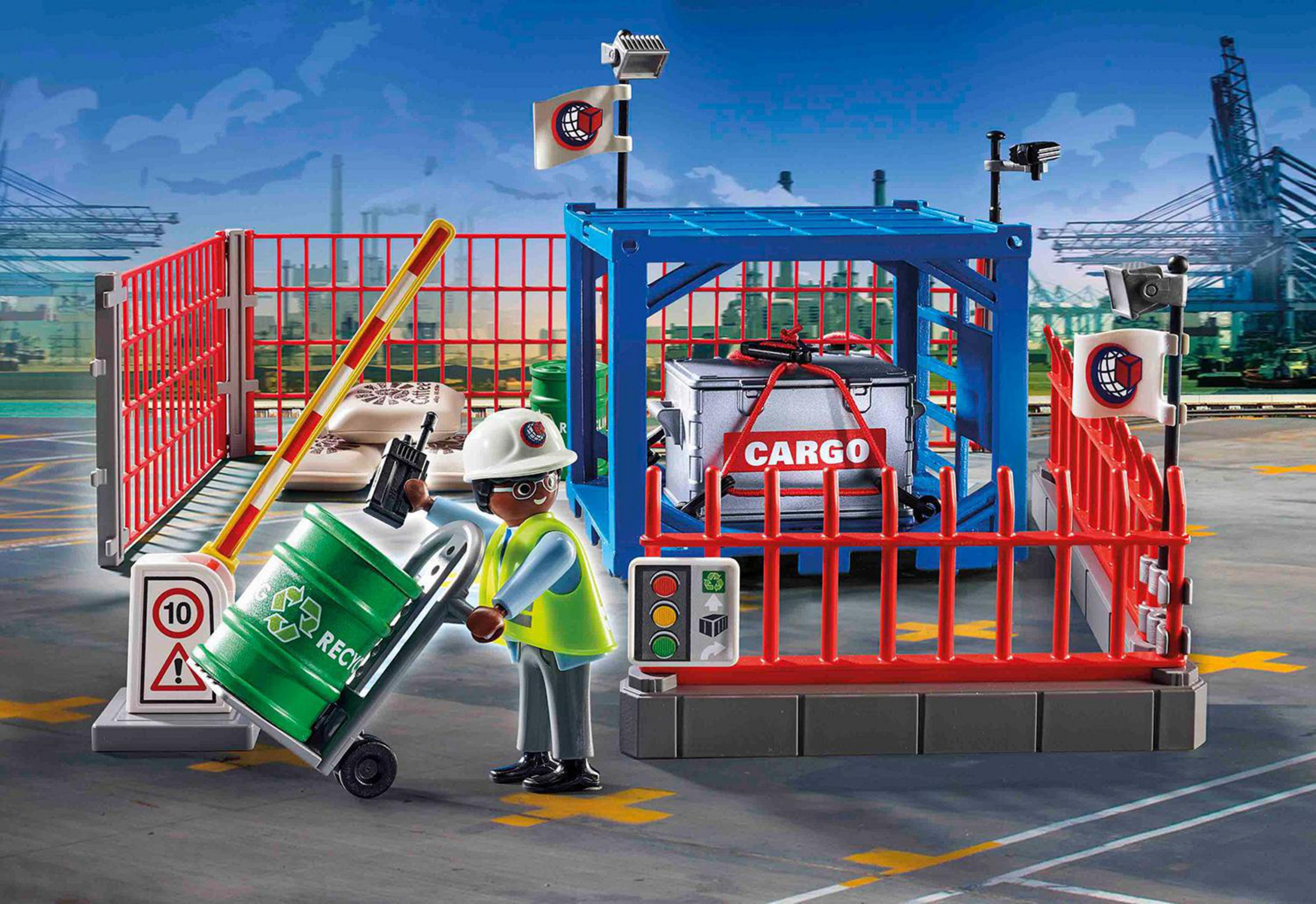 Eine Spielzeug-Frachtszene mit einem Arbeiter, einer Recyclingtonne, einem blauen Container und einer roten Barriere.