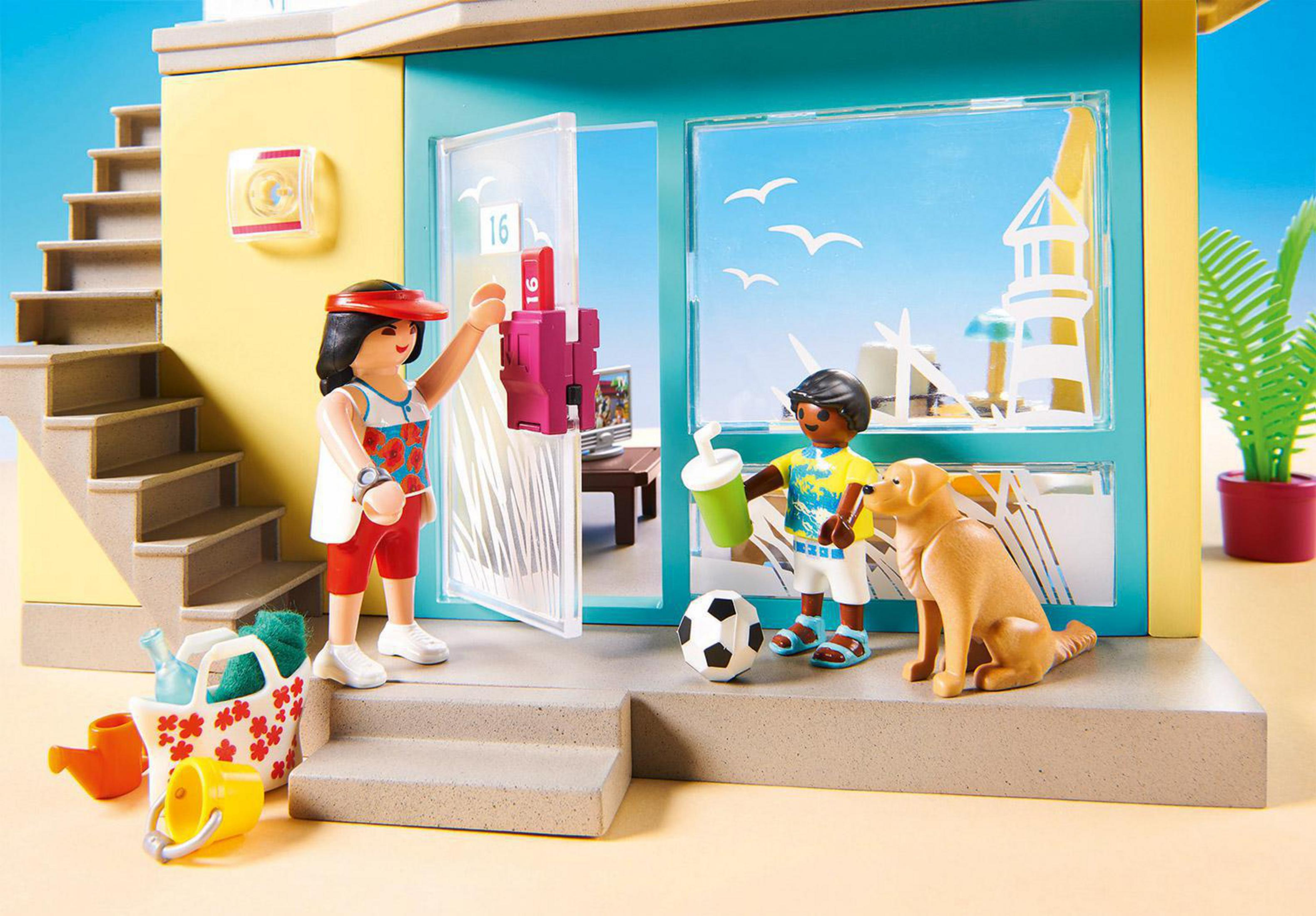 Una escena de juguete de una casa con un niño, una mujer, un perro y accesorios de playa.
