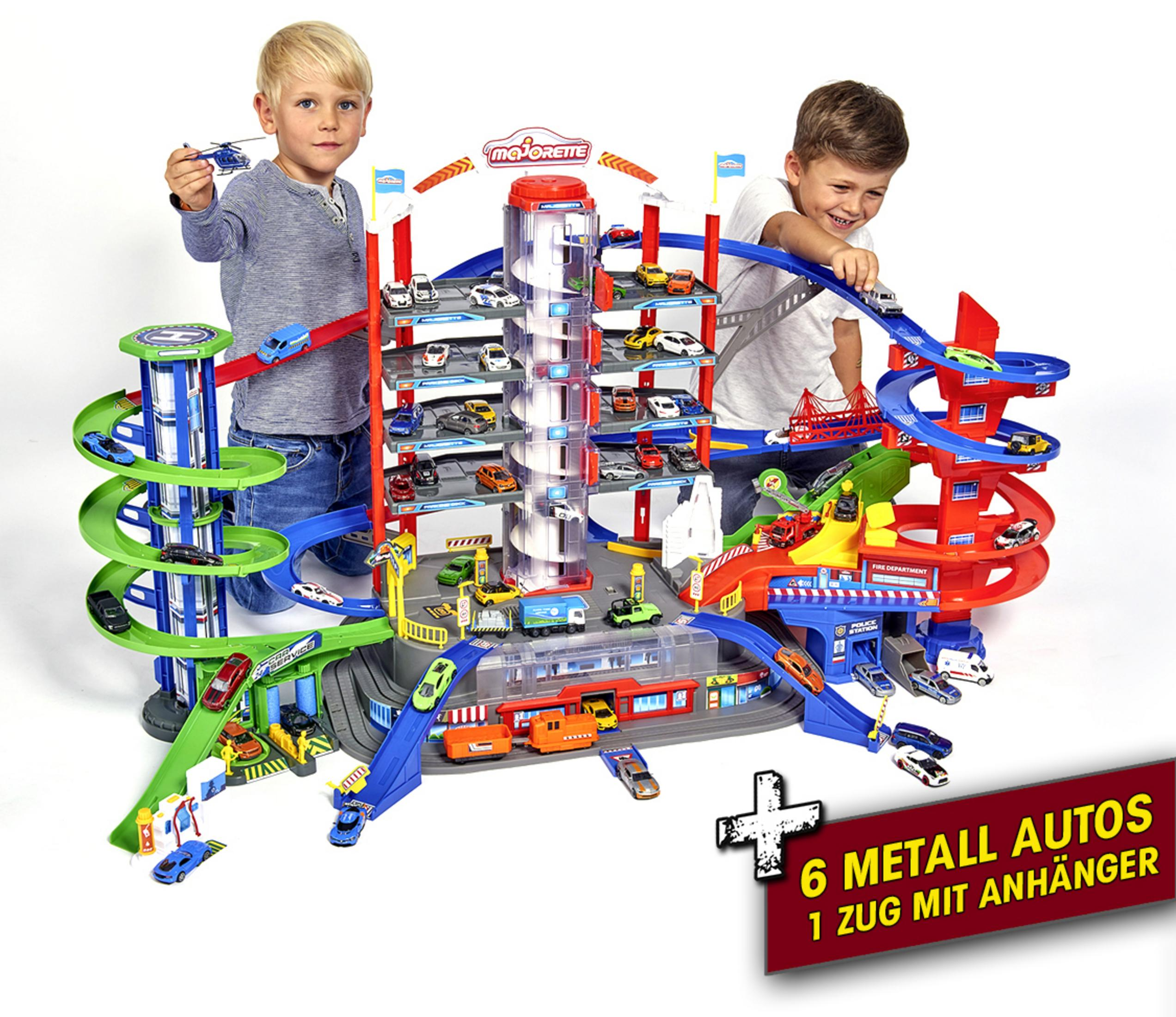 Zwei Jungen spielen mit einer großen Spielzeug-Autogarage mit Autos und einem Hubschrauber.