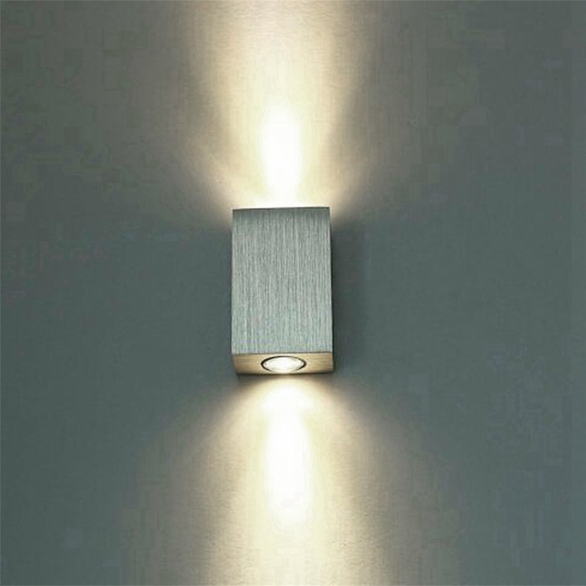 Eine silberne, rechteckige Wandleuchte mit zwei Lichtern, die die Wand beleuchten.