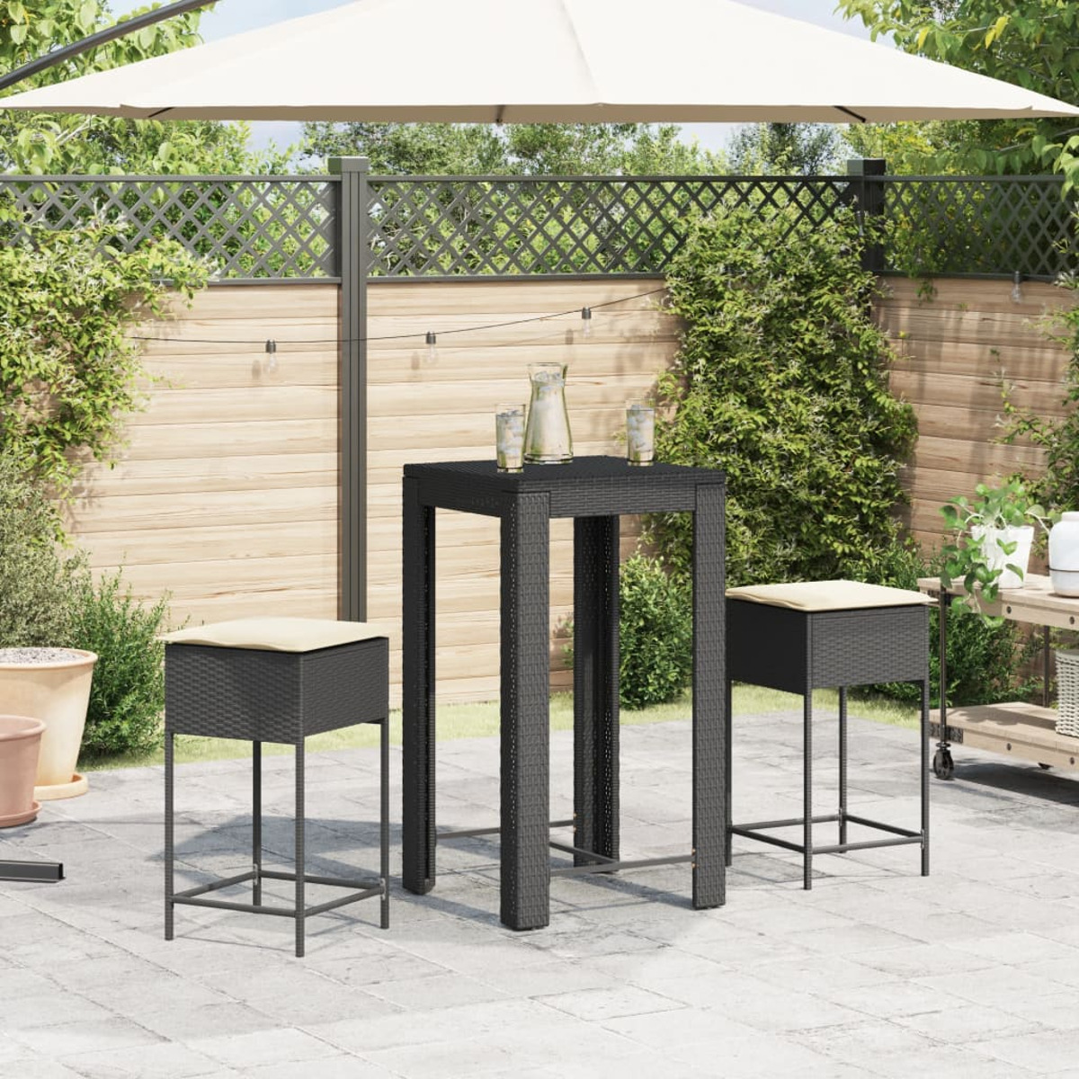 Set da pranzo all'aperto con tavolo nero, due sgabelli e un ombrellone su un patio pavimentato.