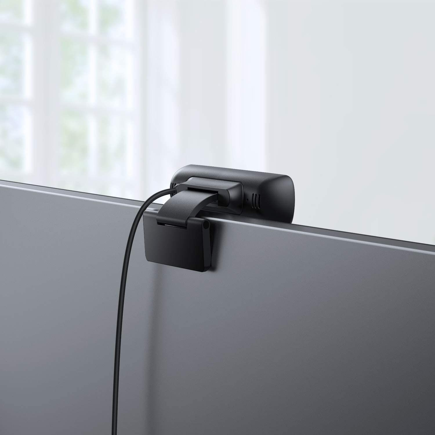 Eine schwarze Webcam, die an einem schwarzen Monitor befestigt ist, mit einem Kabel nach unten.