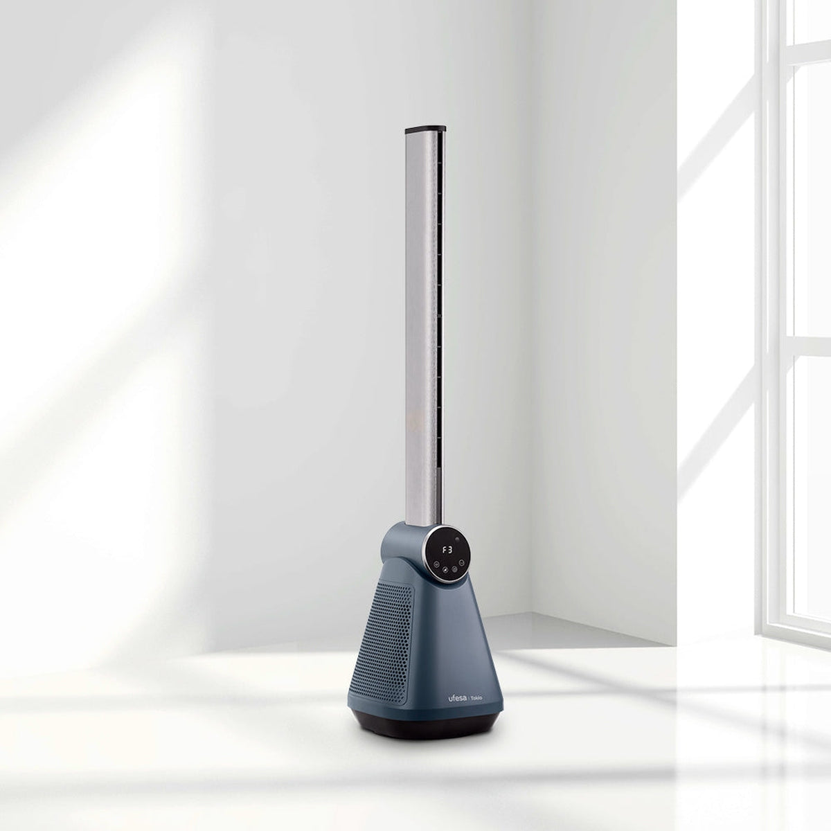 Un ventilador de torre azul con la parte superior plateada, cerca de una ventana, fondo blanco, diseño minimalista.