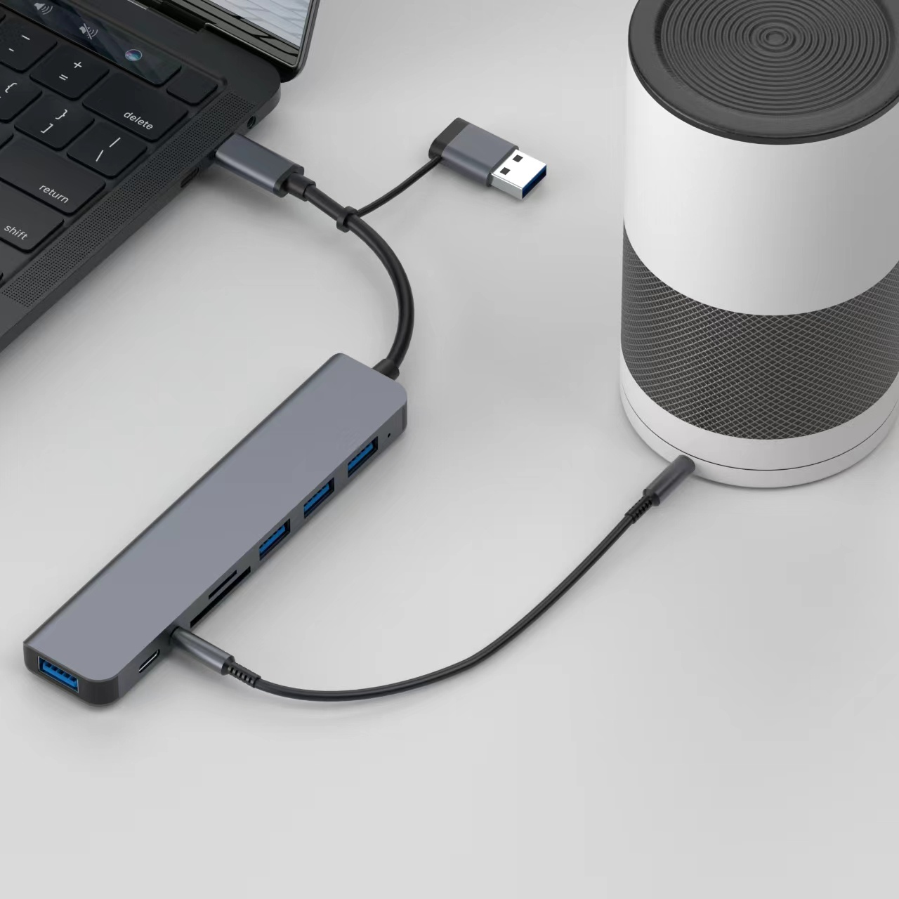 Laptop mit Hub, USB- und Stromkabeln verbunden, dazu ein Lautsprecher.
