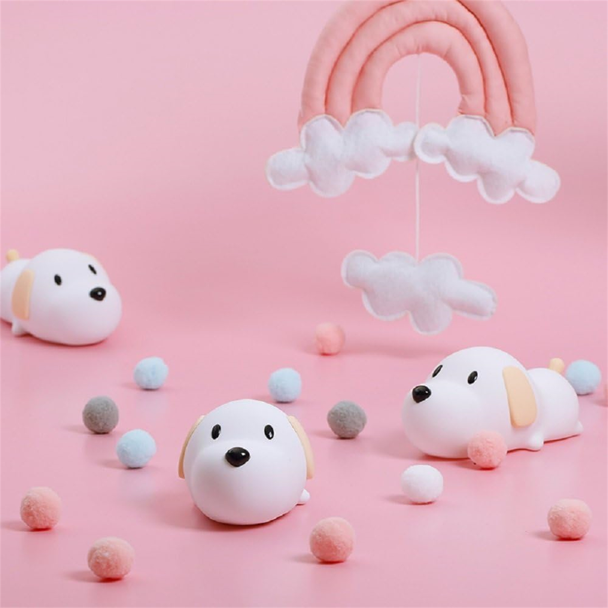 Rosa Hintergrund mit Hunde-Spielzeug, Regenbogen-Mobile und bunten Pompons.