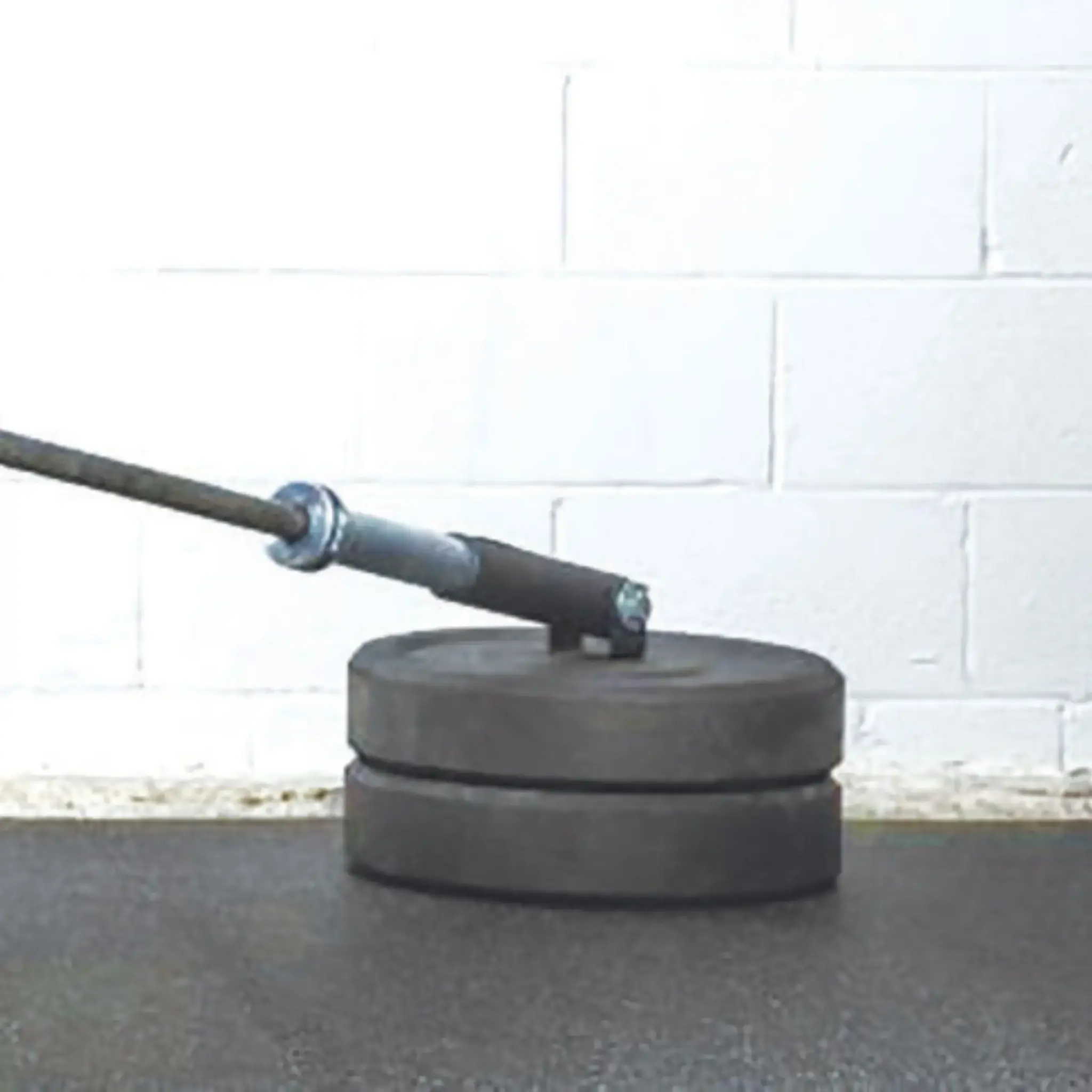 Weight plates with a barbell attached, on a gym floor.
