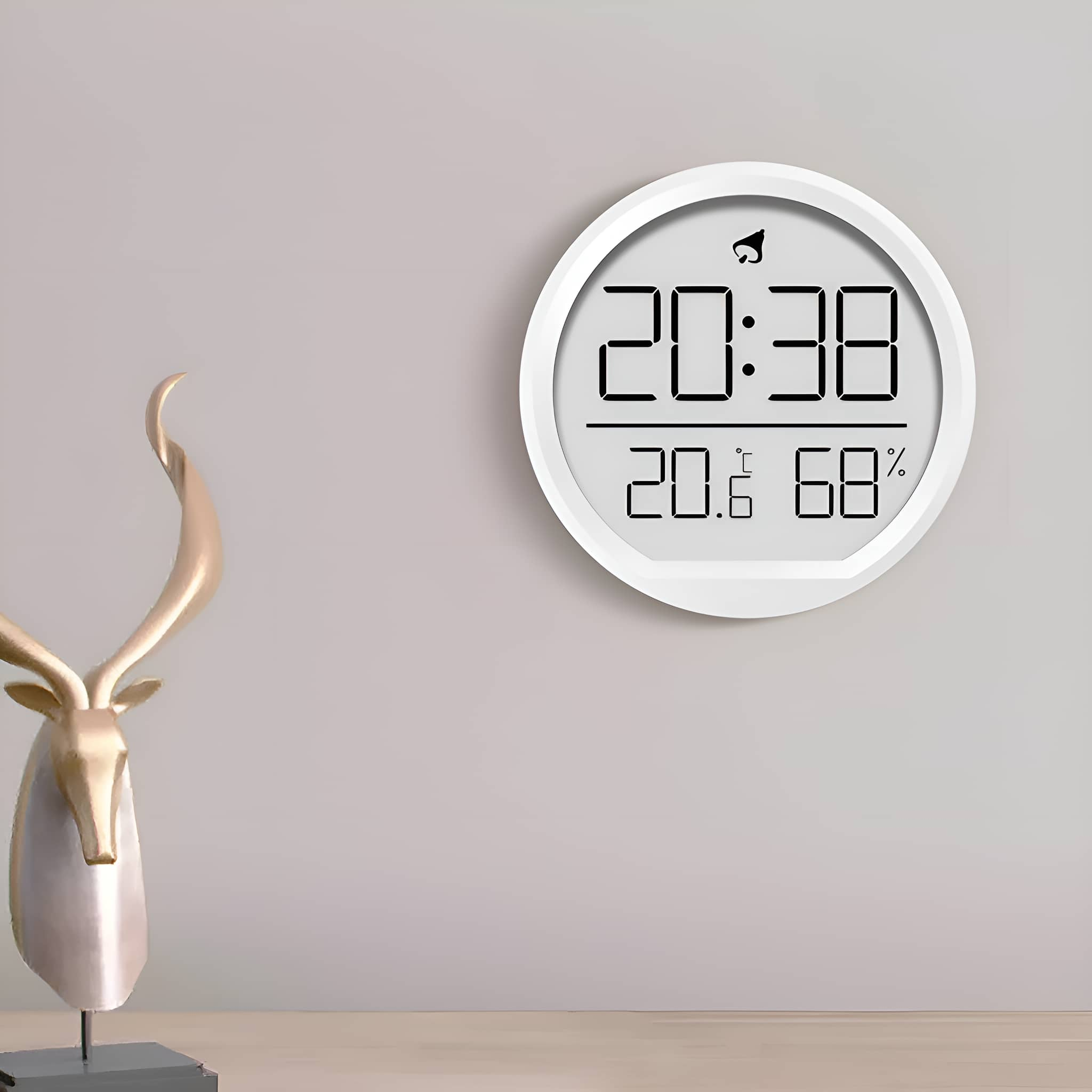 Weisse Digitaluhr mit Zeit- und Feuchtigkeitsanzeige, mit goldener Hirschstatue im Vordergrund.