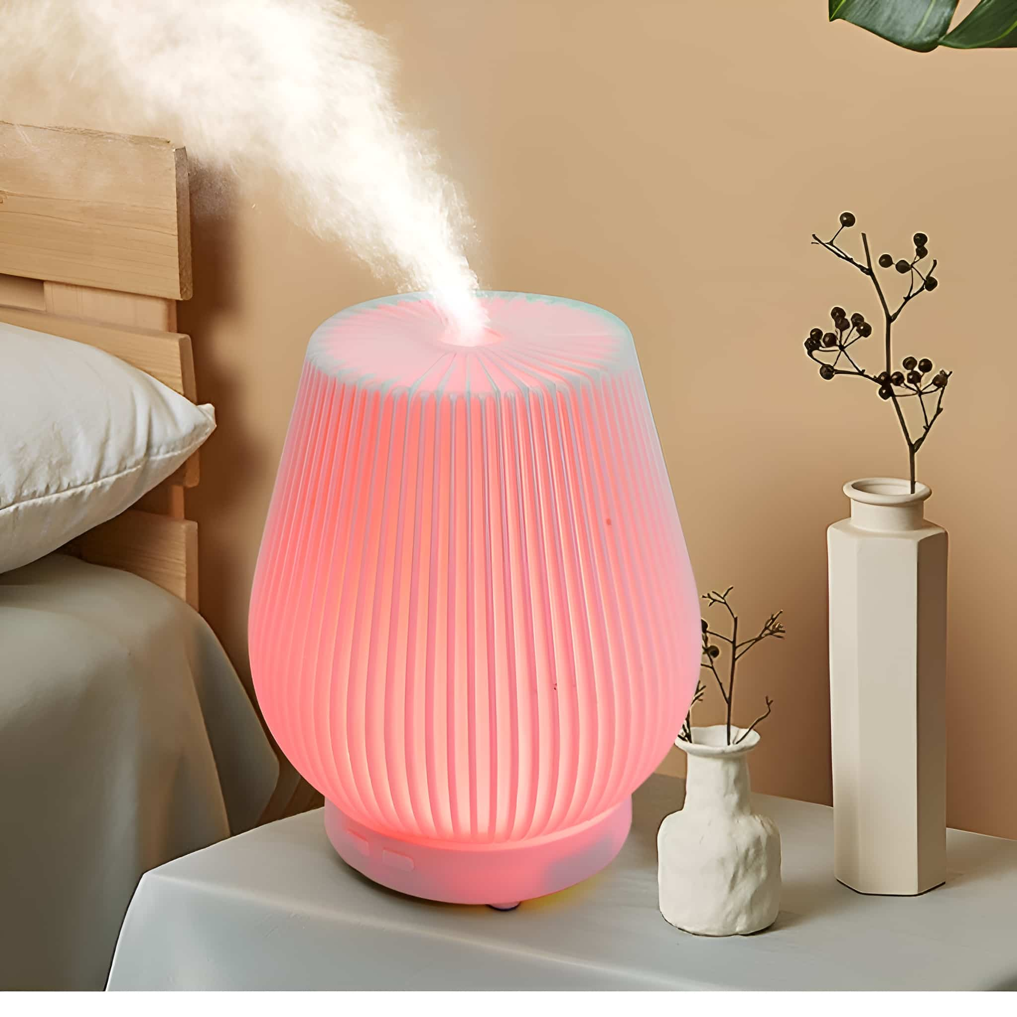 Diffusor, der Dampf abgibt, beleuchtet mit rosa Licht. Zwei Vasen und ein Holzbettrahmen im Hintergrund.