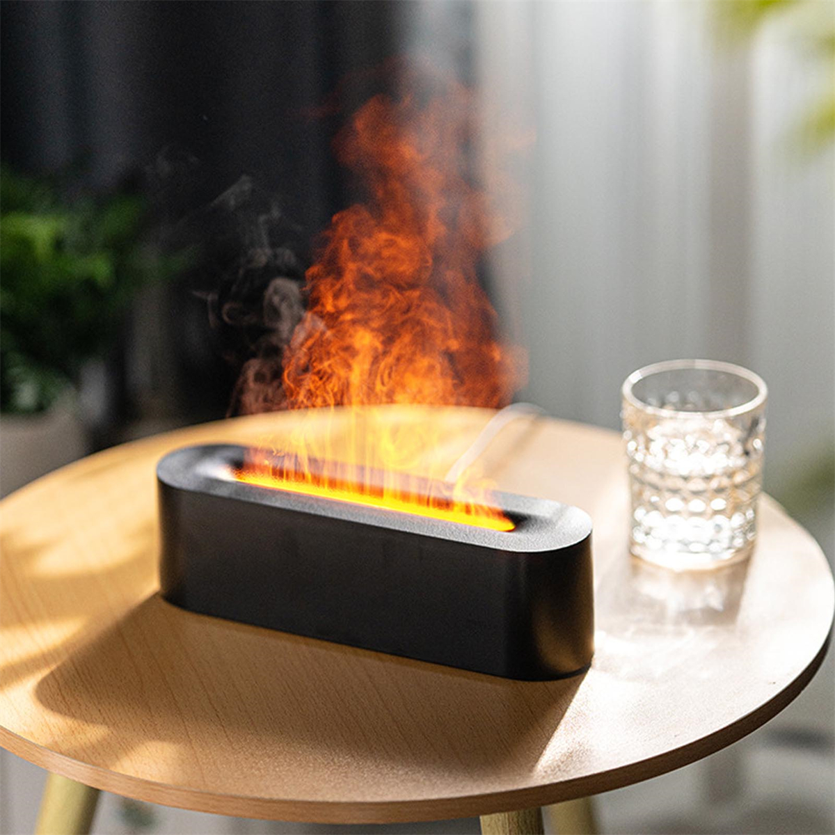 Schwarzer, oval geformter Luftbefeuchter mit orangefarbenem Flammeneffekt, auf einem Holztisch.
