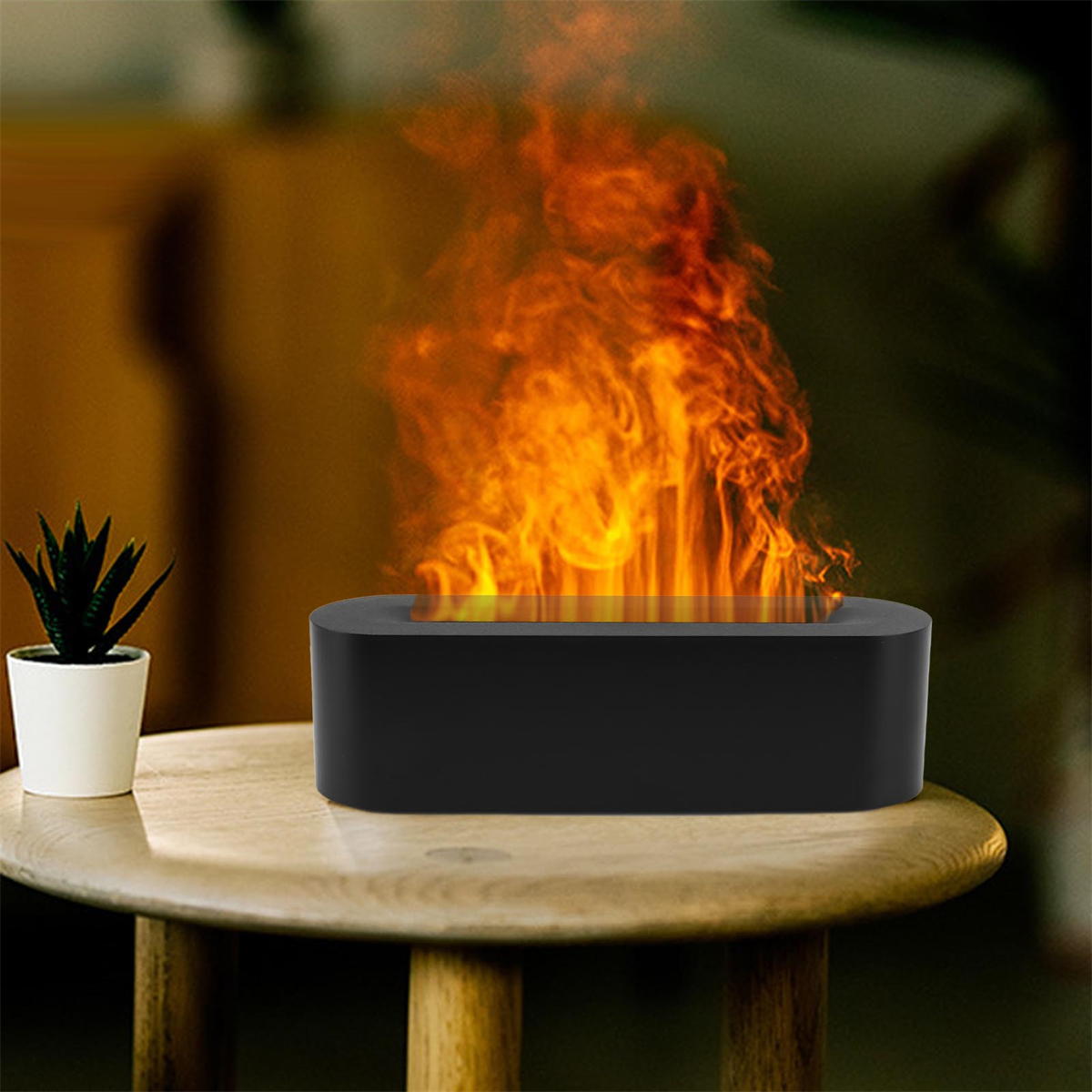 Ein schwarzes Gerät emittiert orange Flammen auf einem Tisch. Links steht eine kleine Pflanze.