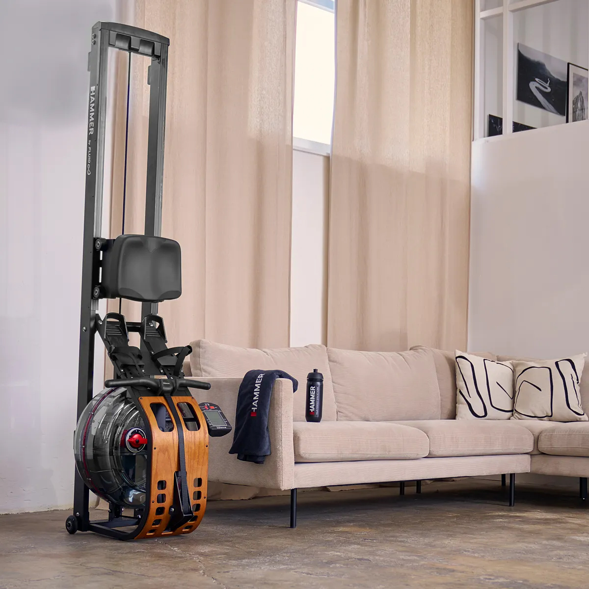 Rudergerät mit Wassertank und Holzakzenten, ein Sofa und Fenster mit Vorhängen.