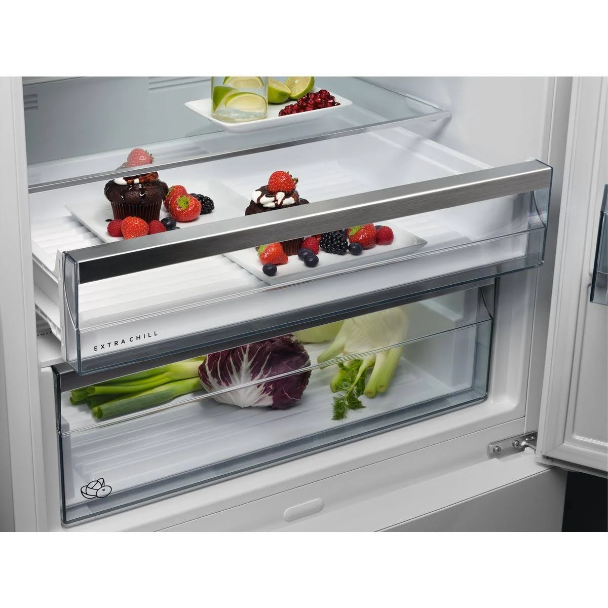 Interieur van een koelkast met lades. Bevat fruit, groenten en desserts op planken.