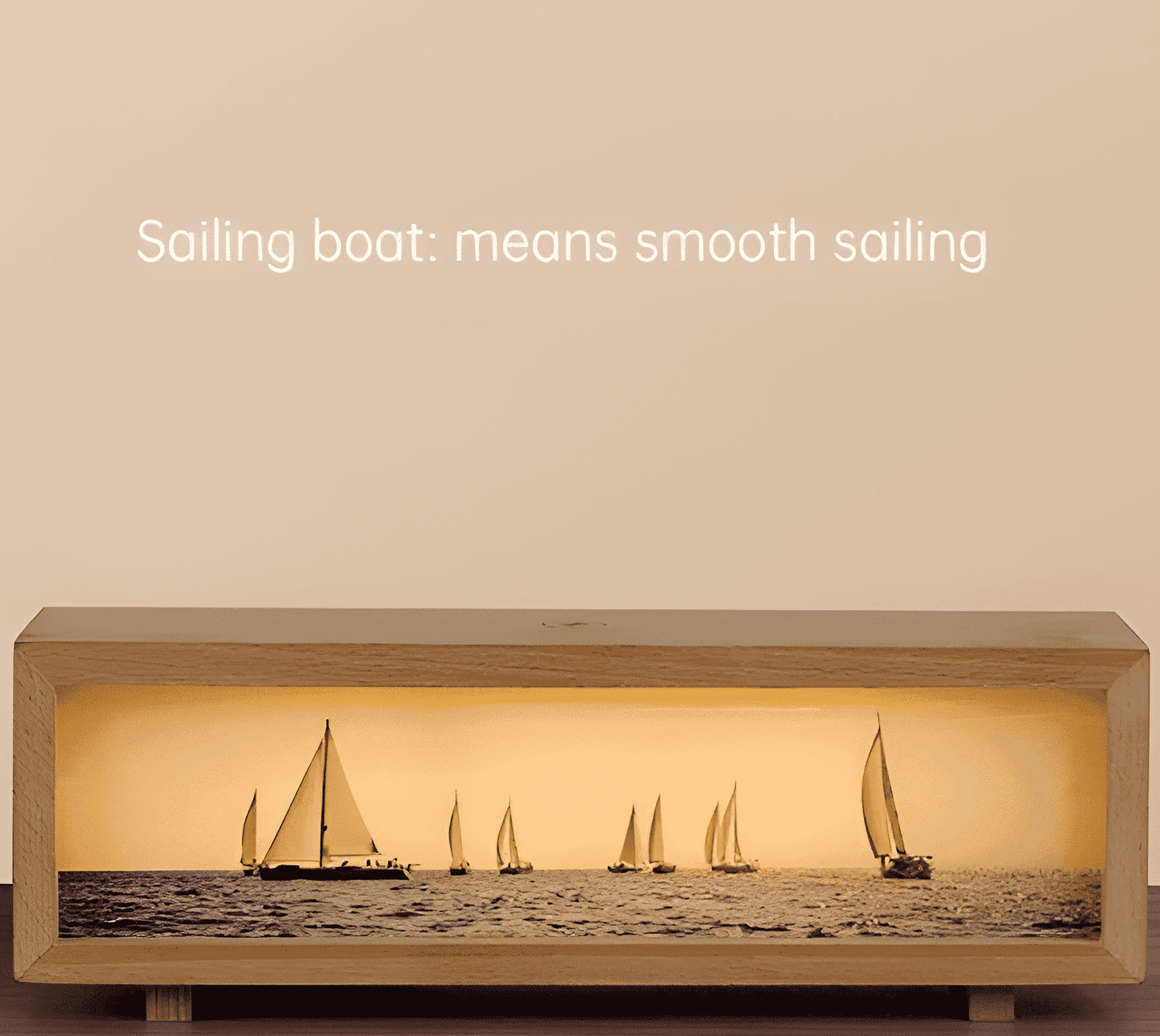 Eine hölzerne Lichtbox, die eine Seelandschaft mit Segelbooten zeigt. Text: 'Segelboot: bedeutet reibungslose Fahrt'.