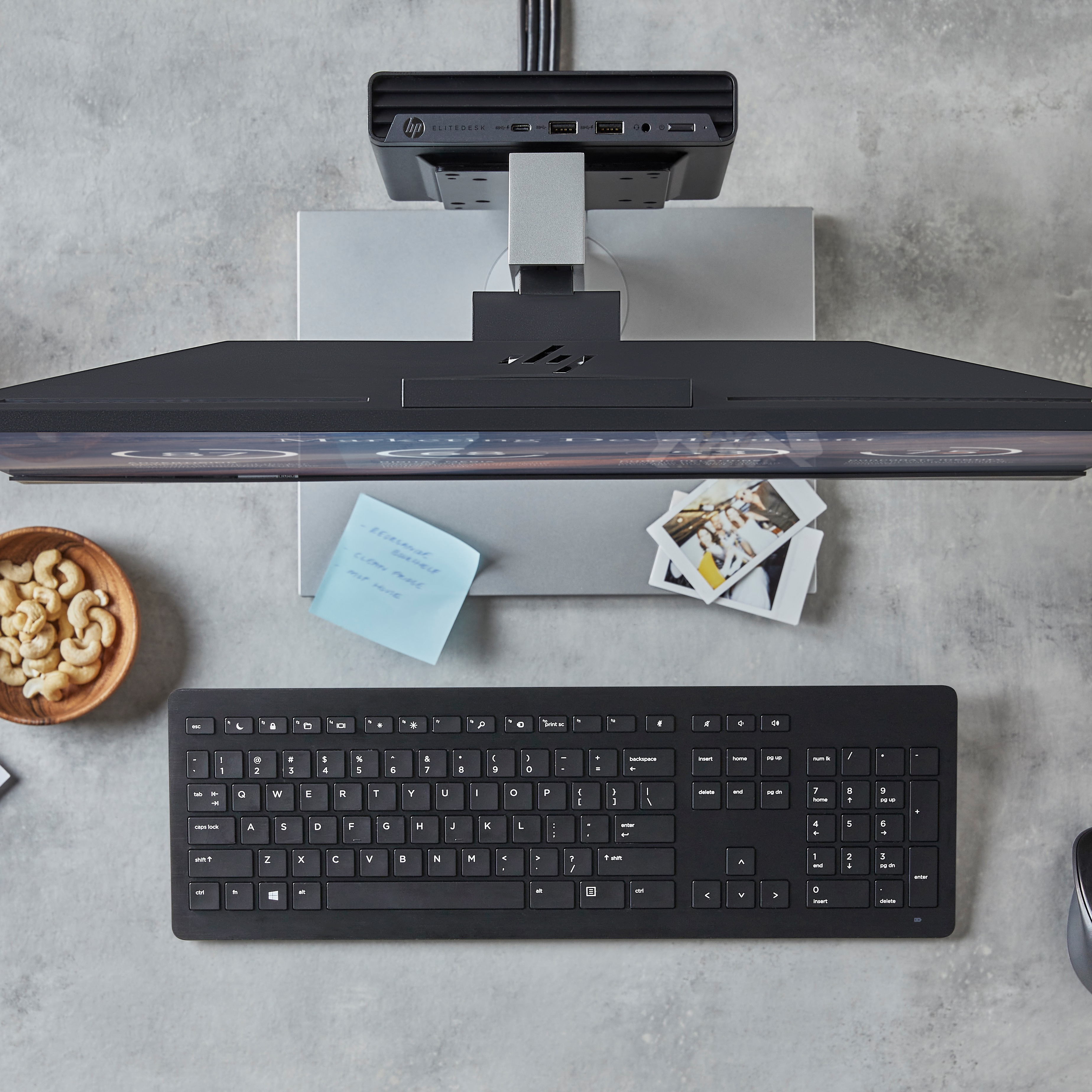 Widok z góry na biurko z monitorem, klawiaturą i przekąskami.