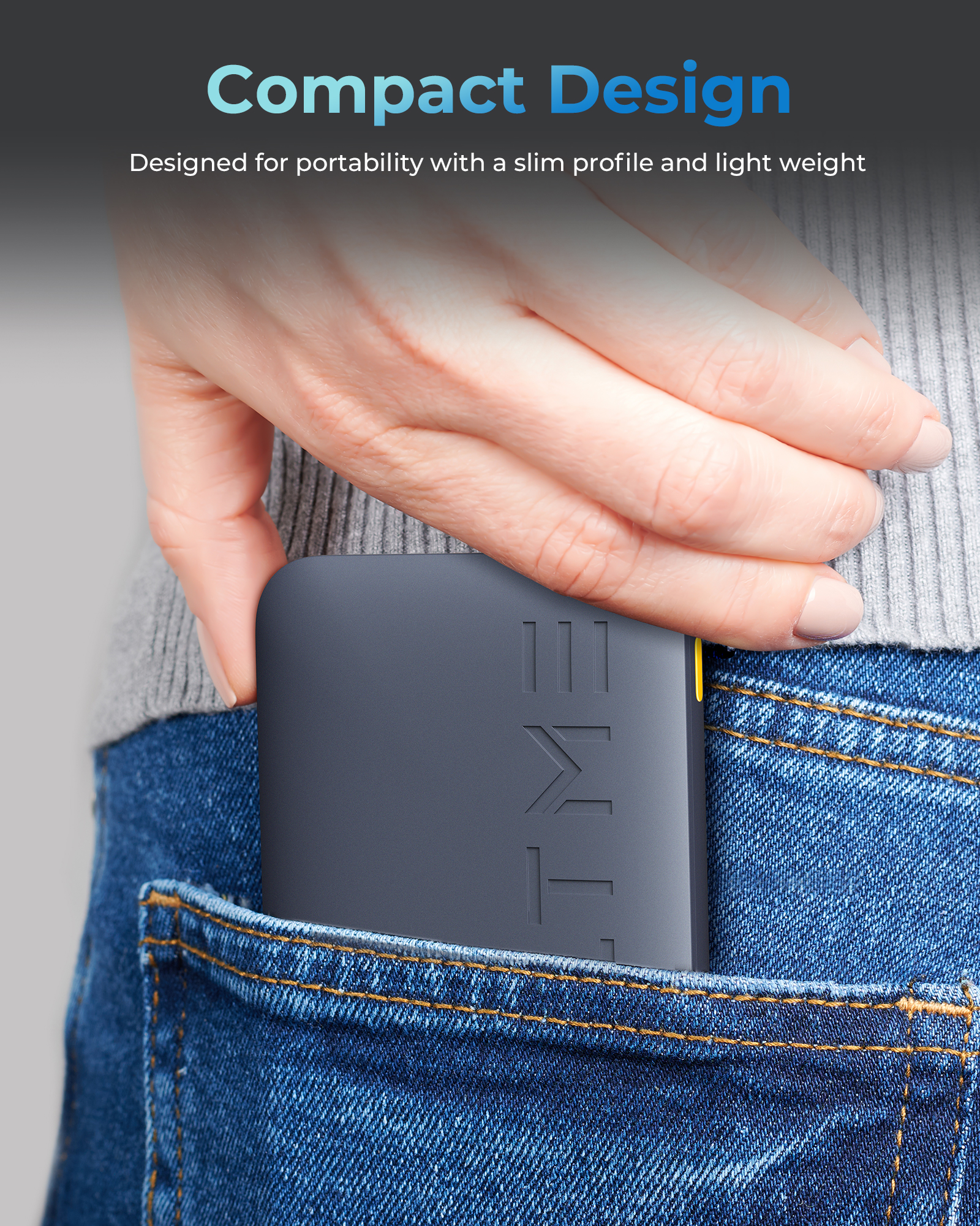 La mano di una persona che tiene un piccolo dispositivo grigio scuro in una tasca di jeans.