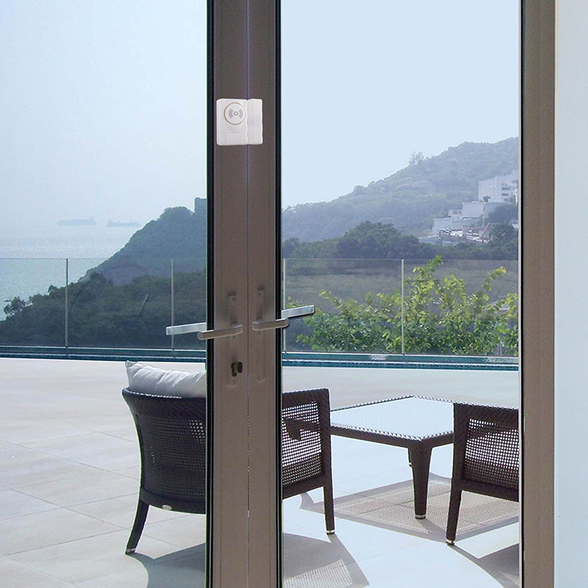 Glastür mit Sensor. Ein Stuhl und ein Tisch sind auf der Terrasse im Hintergrund sichtbar.