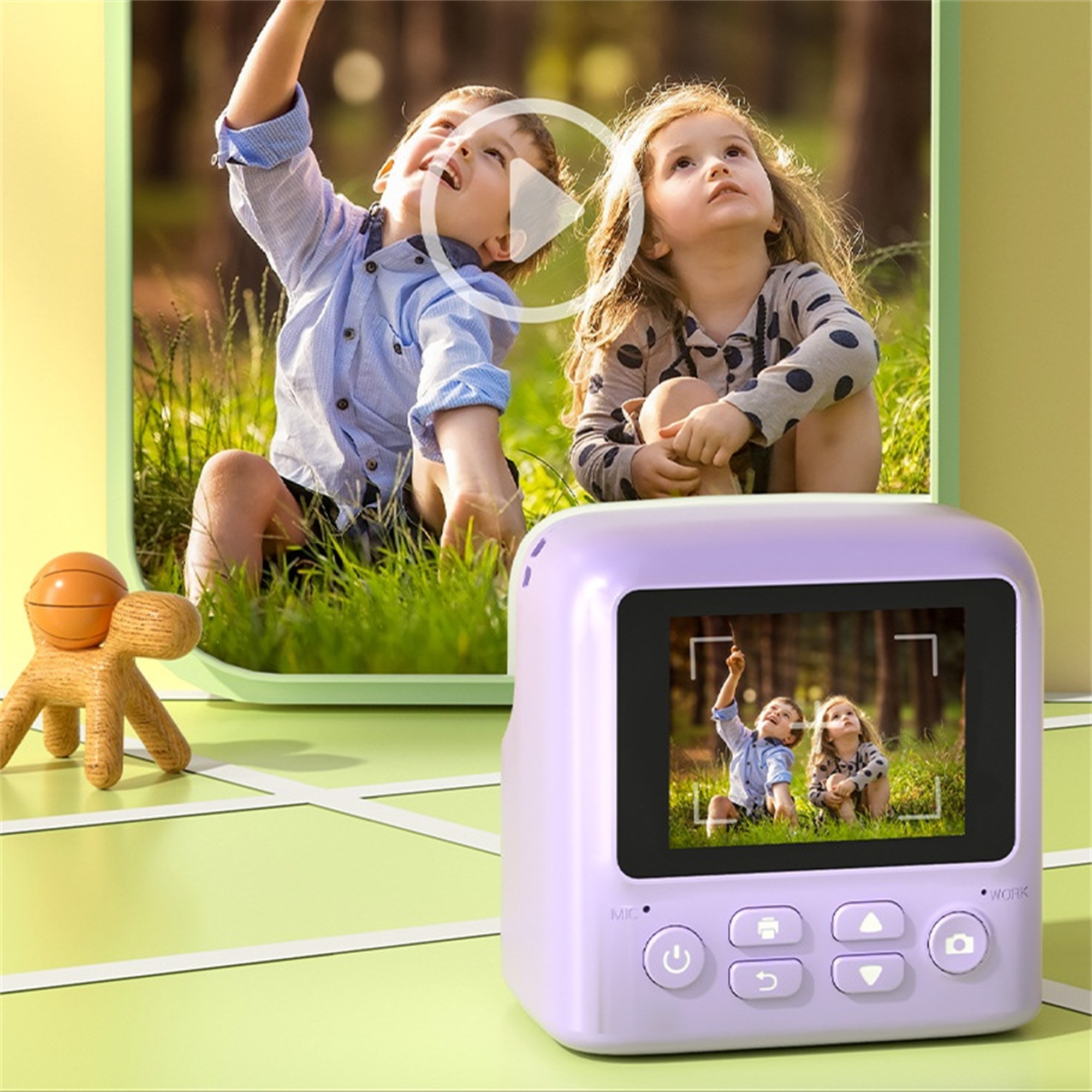 Eine violette Sofortbildkamera mit Bildschirm, zeigt ein Bild. Zwei Kinder schauen nach oben. Hintergrund grün und gelb.