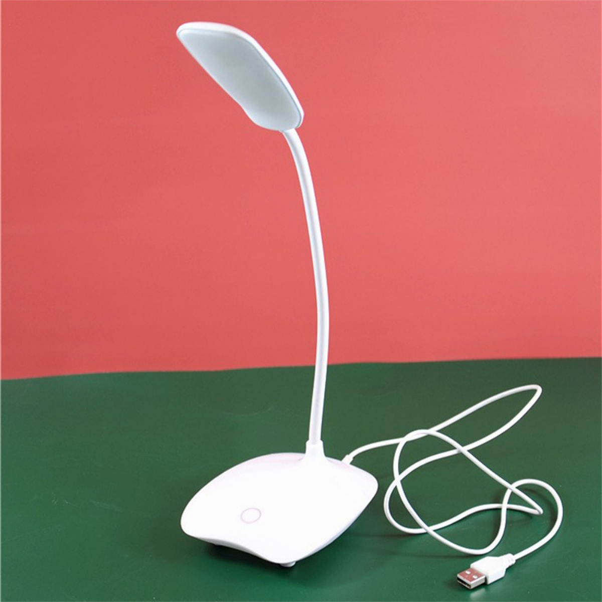 Weiße Schreibtischlampe mit flexiblem Hals und USB-Kabel, roter und grüner Hintergrund.