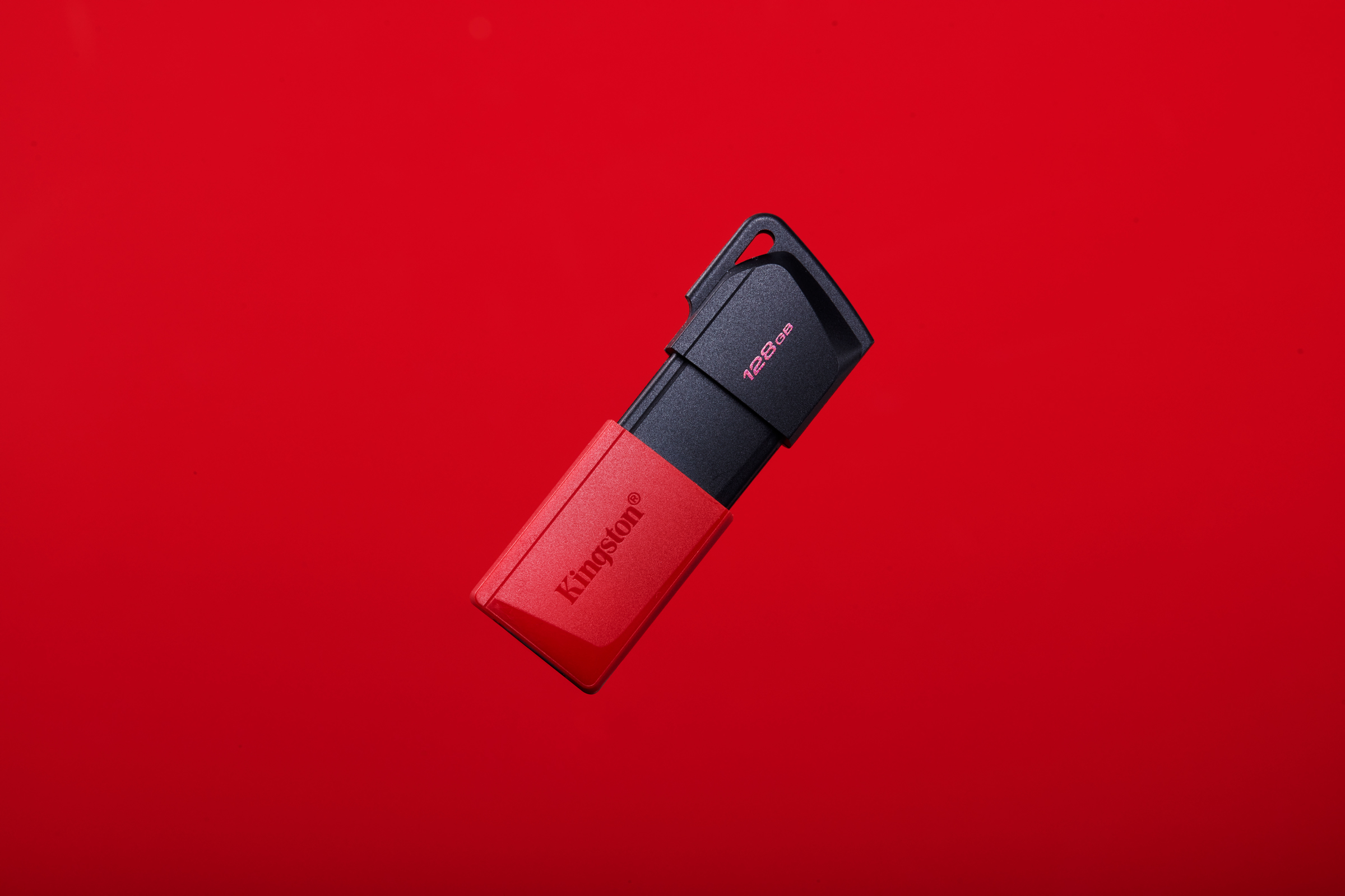 Czerwony i czarny pendrive Kingston na czerwonym tle.