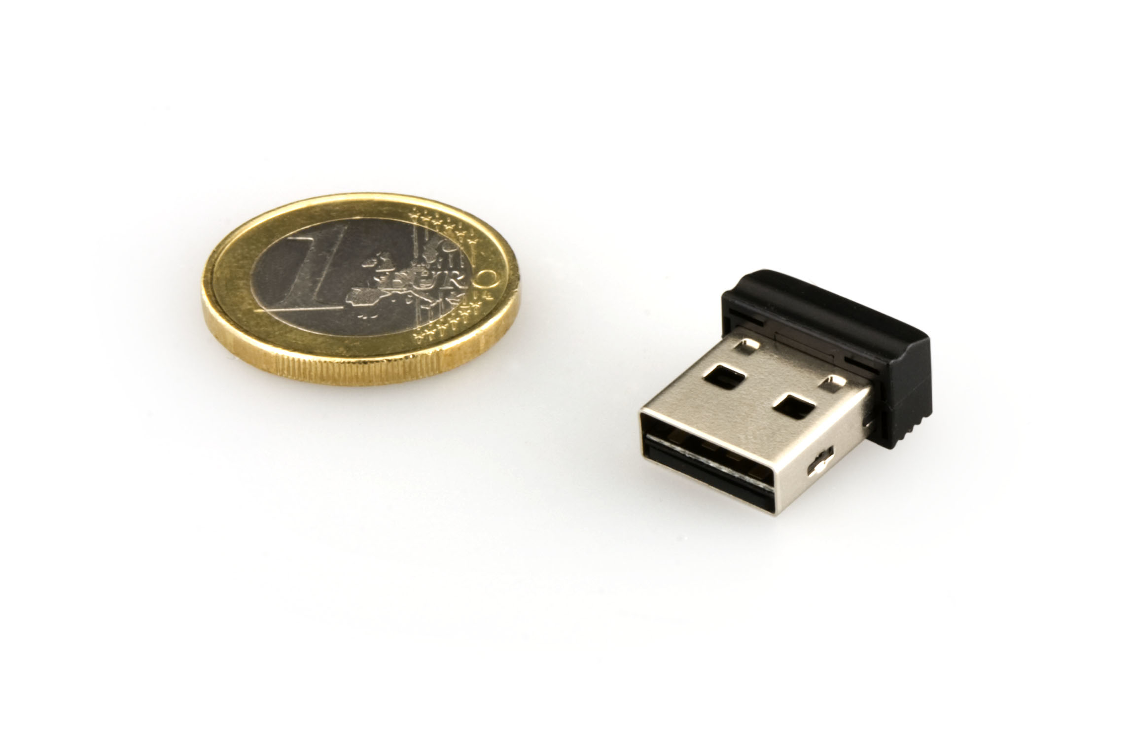Mały pendrive USB obok monety euro. USB jest czarny, a moneta złota.