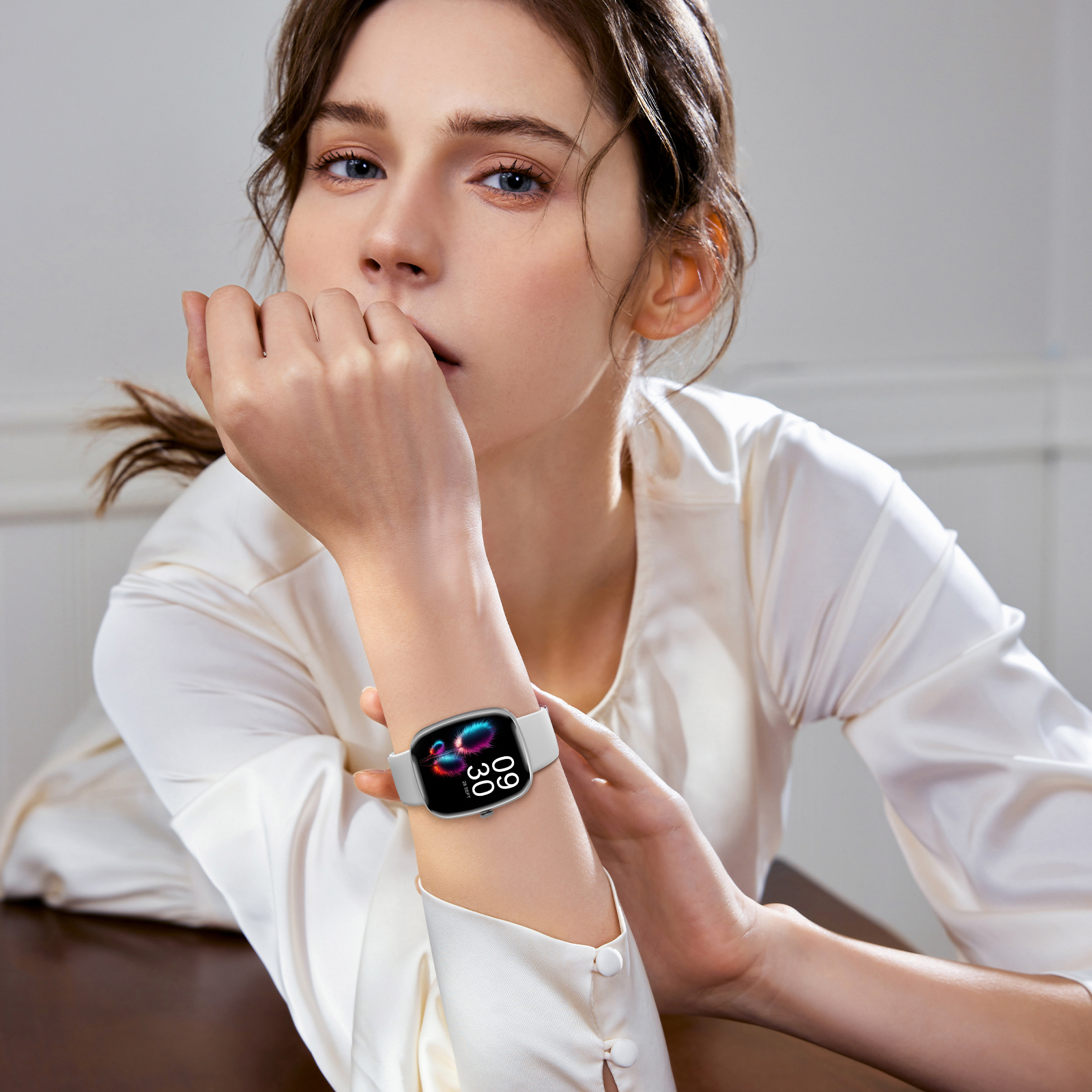 Frau mit einer weißen Smartwatch mit schwarzem und pinkfarbenem Display. Sie hat helle Haut.