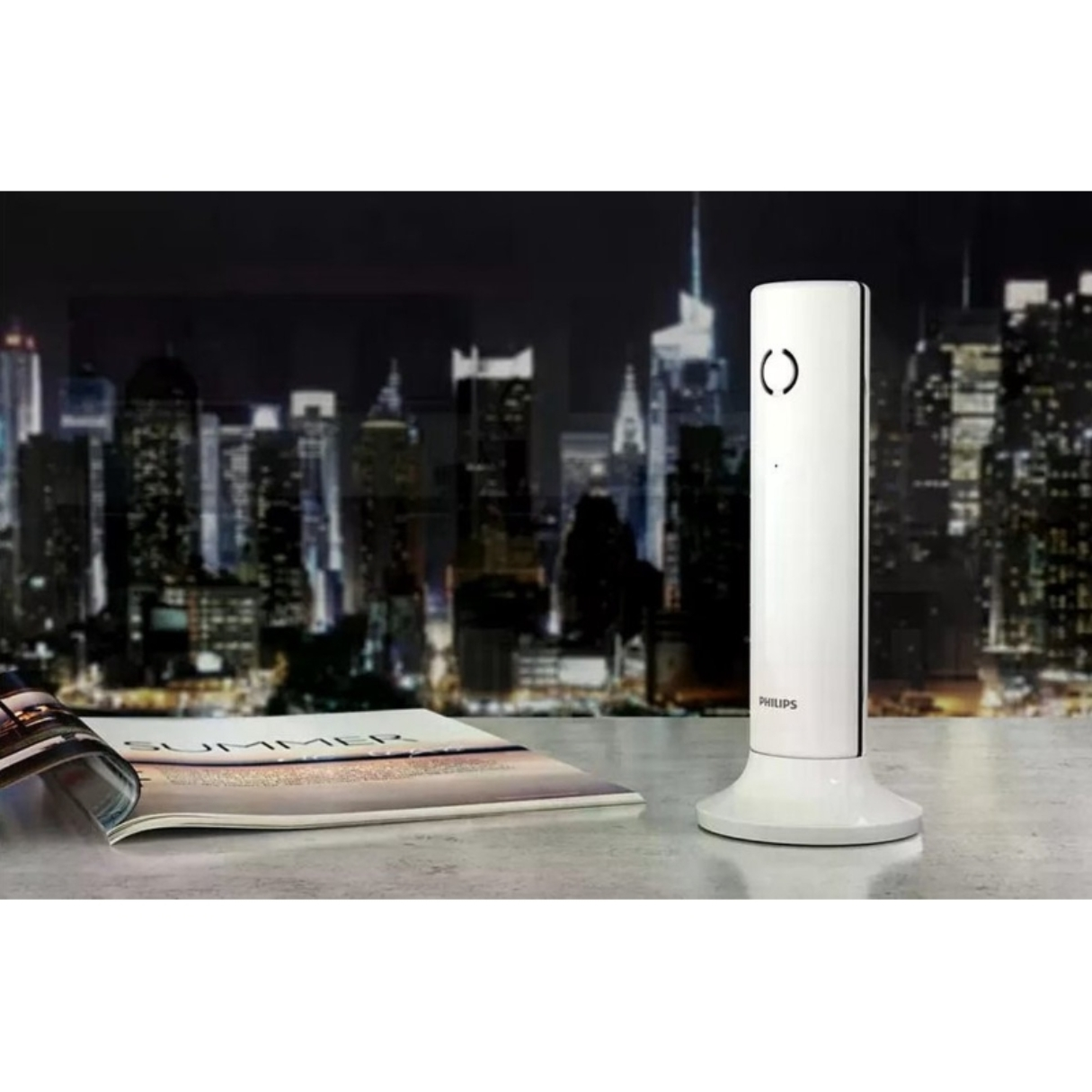 Une base de téléphone Philips blanche avec un téléphone est sur une table. Skyline en arrière-plan la nuit.