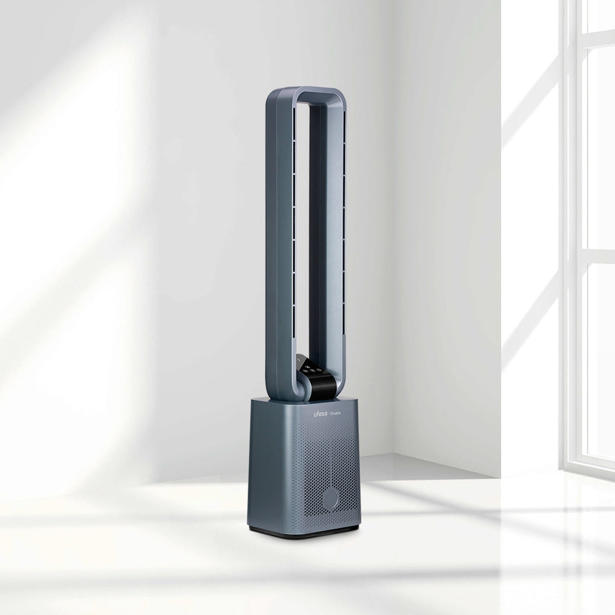 Szary wentylator wieżowy Ufesa, stojący na kwadratowej podstawie. Znajduje się w jasnym pomieszczeniu obok okna.