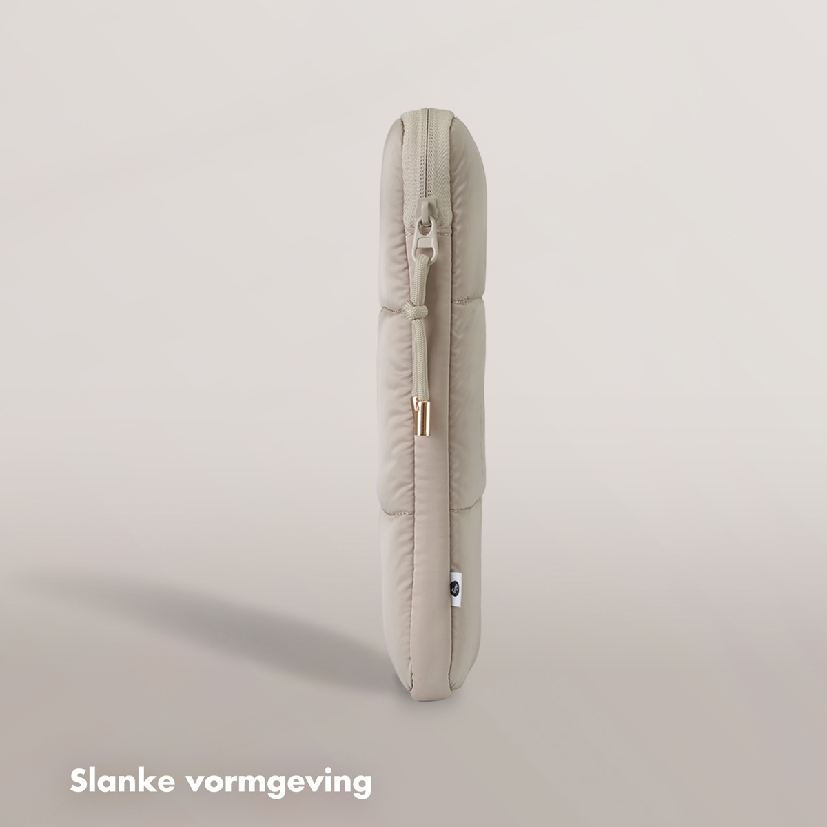 A beige laptop sleeve, standing vertically. It's a quilted, padded case with a zipper and a small label.