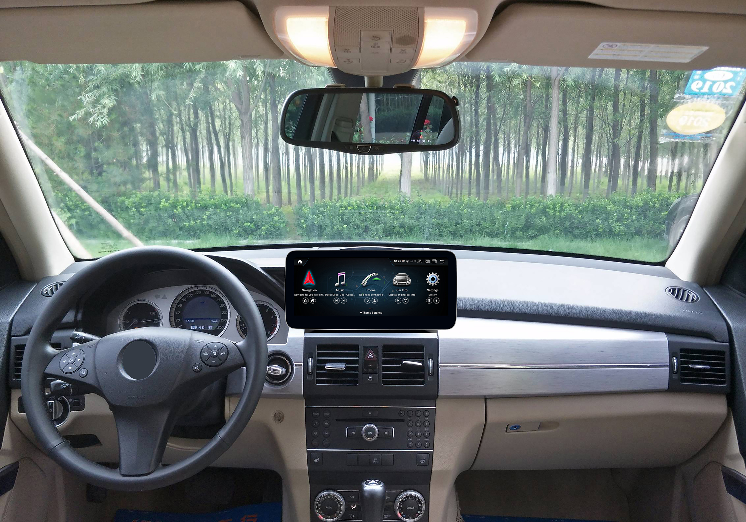 Innenansicht des Autos: Armaturenbrett, Lenkrad, Auto-Infotainmentsystem und Waldblick durch die Windschutzscheibe.