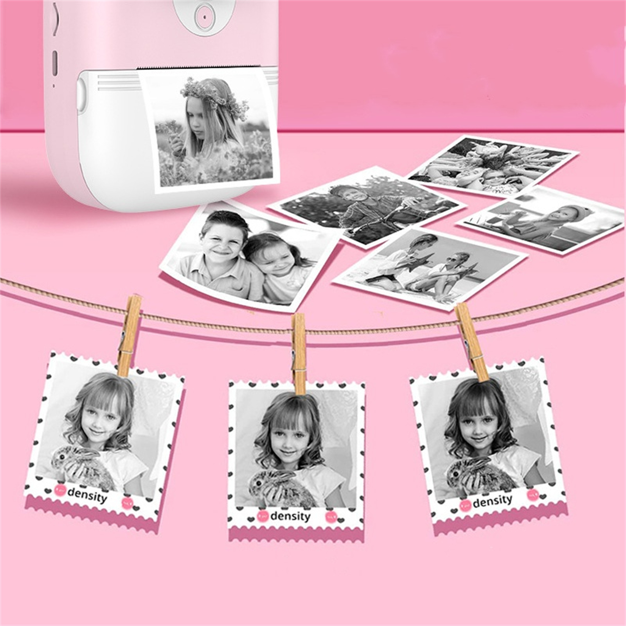 Ein rosa Mini-Fotodrucker mit Fotos, die an einer Leine mit Wäscheklammern hängen.