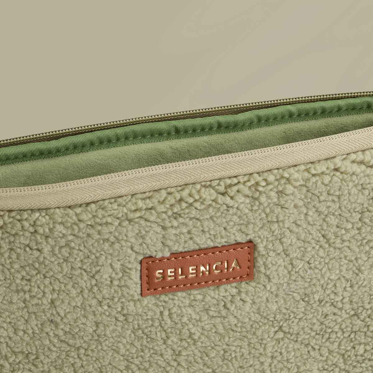 Close-up of a laptop sleeve. The sleeve is light green with a brown leather label that says SELENCIA.