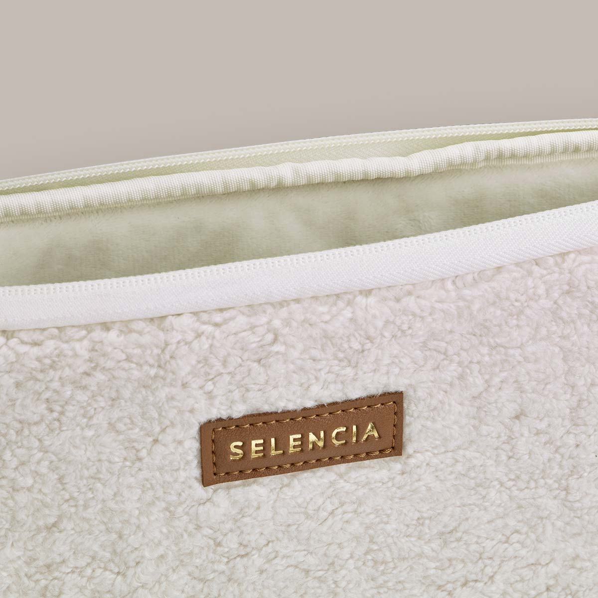 Close up of a laptop case, revealing the inner lining and a brown leather tag.