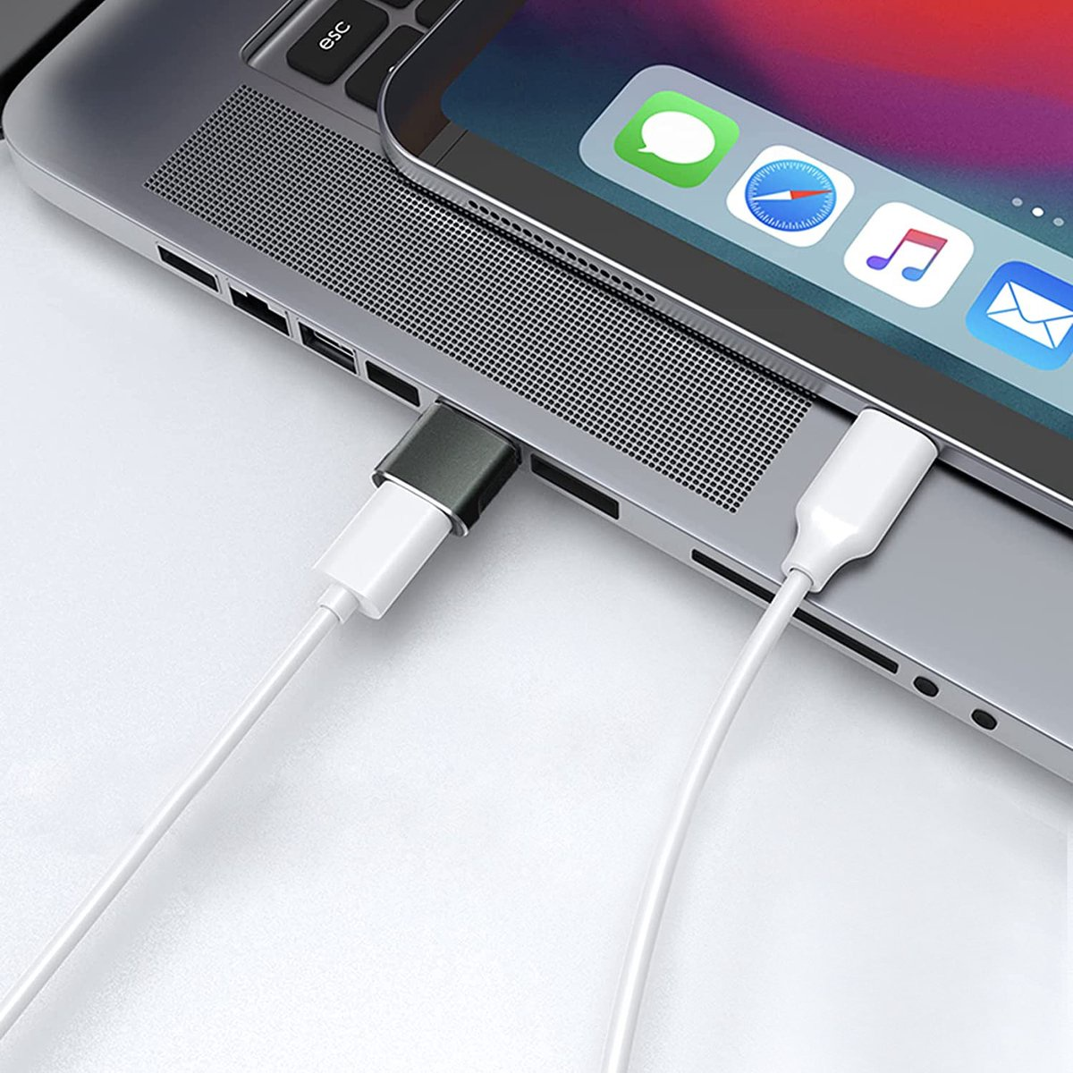 Ordinateur portable avec une tablette dessus, connectés par des câbles blancs et gris.