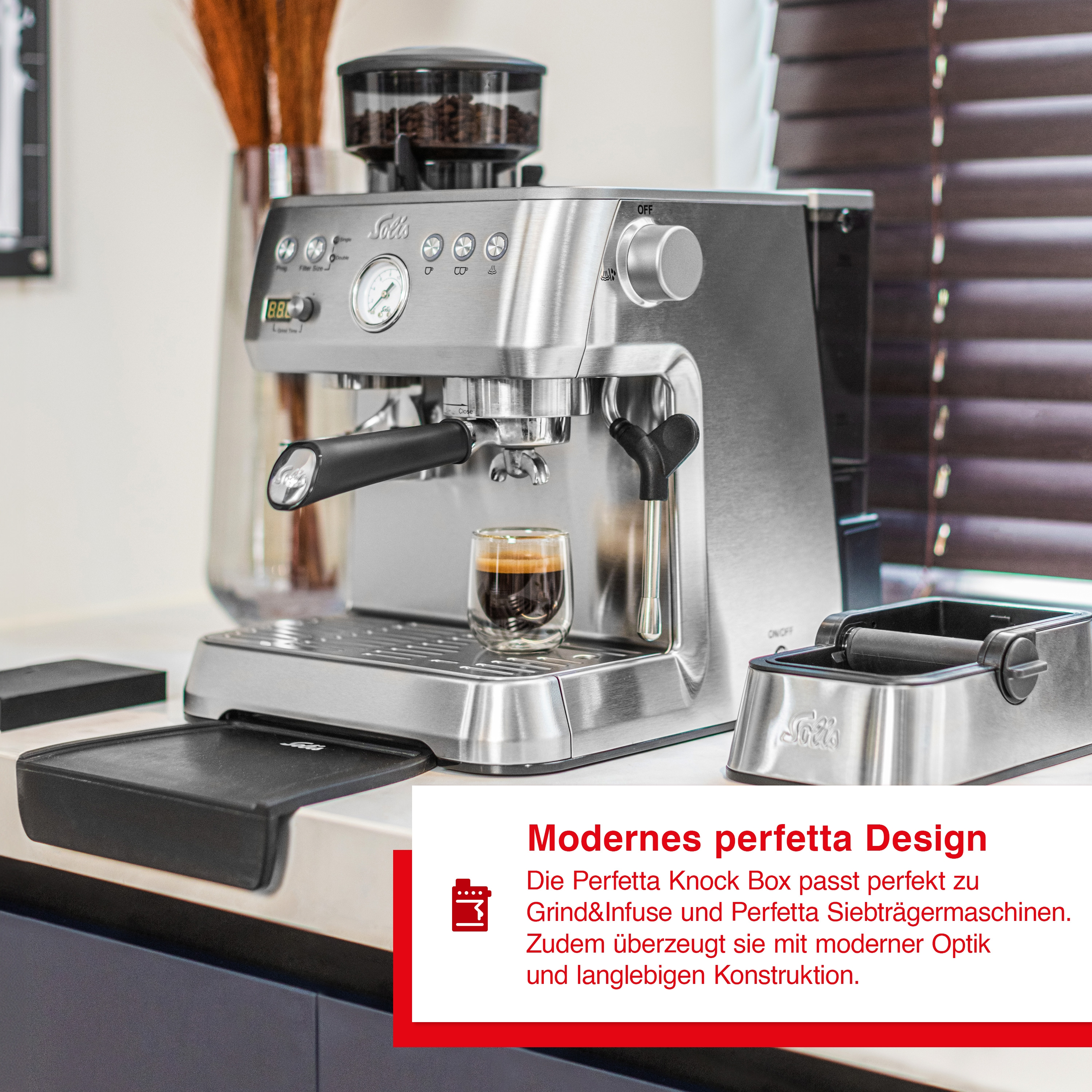 Espressomaschine aus Edelstahl mit Kaffeeglas und Knock-Box auf der Theke.
