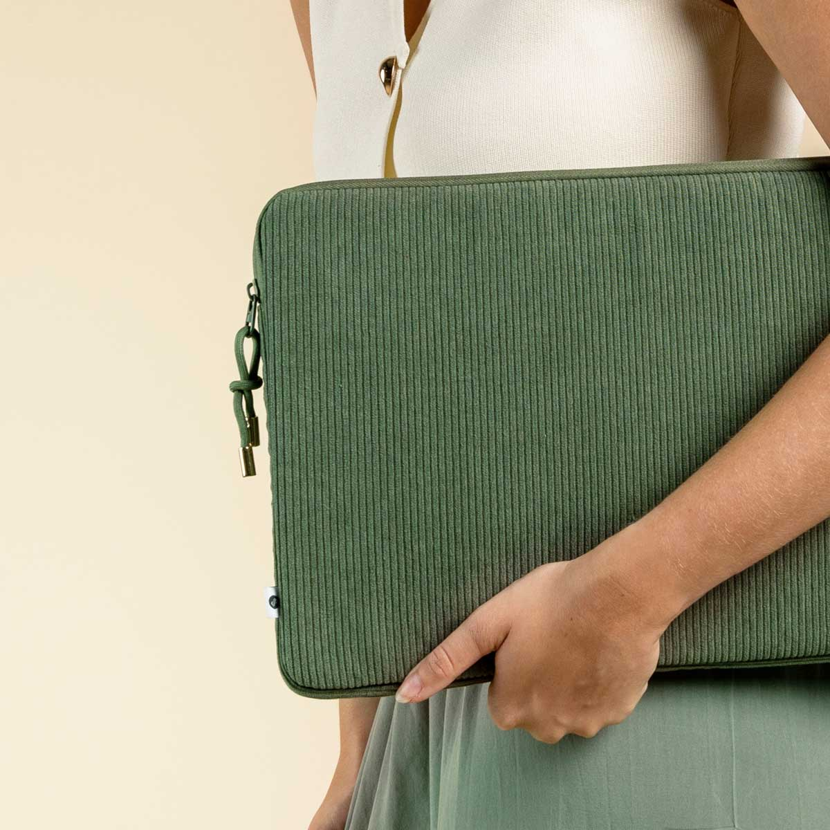 Woman holding a green corduroy laptop sleeve.