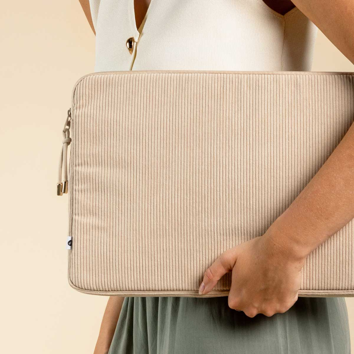 Person holding a beige corduroy laptop sleeve.