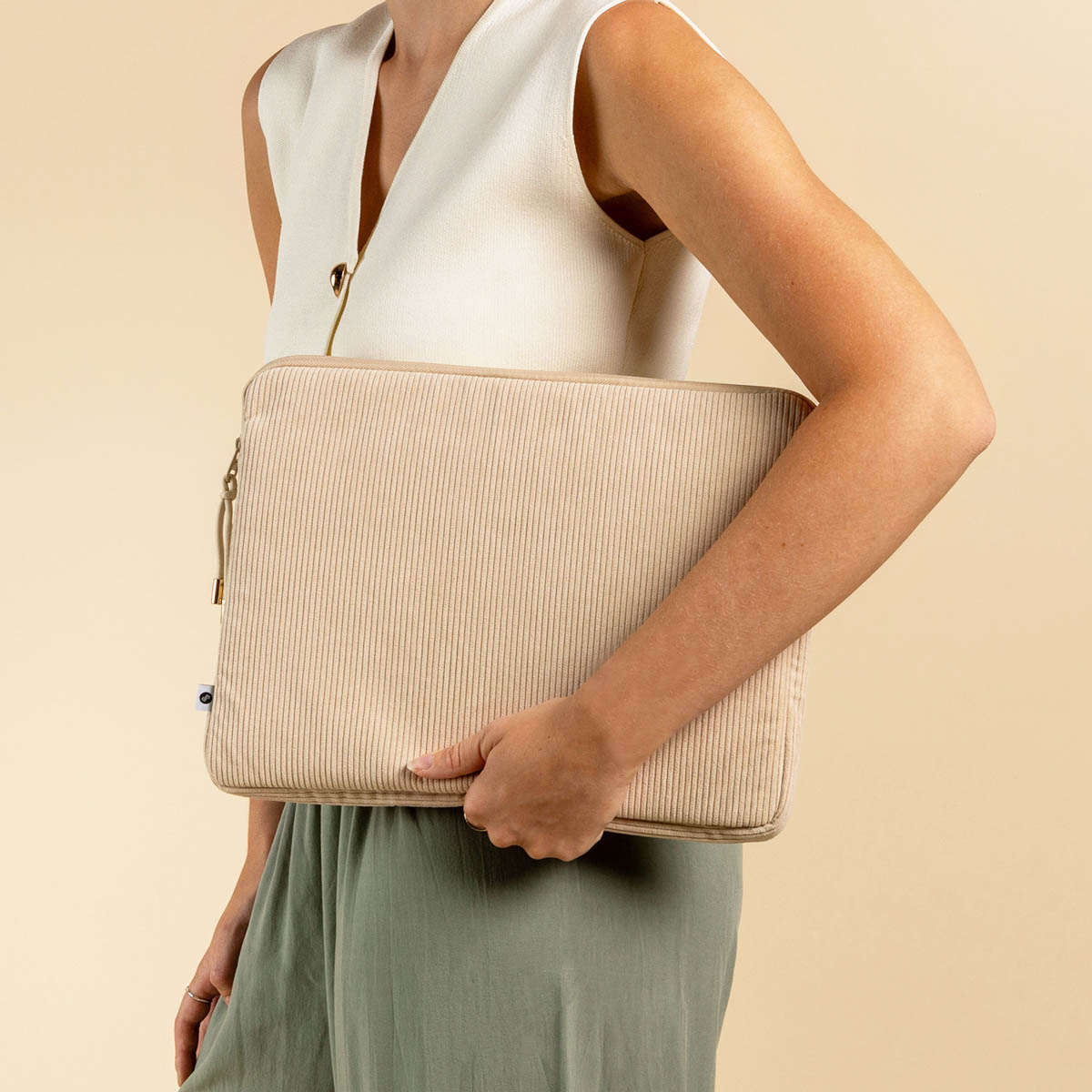 Woman holding a beige corduroy laptop case.