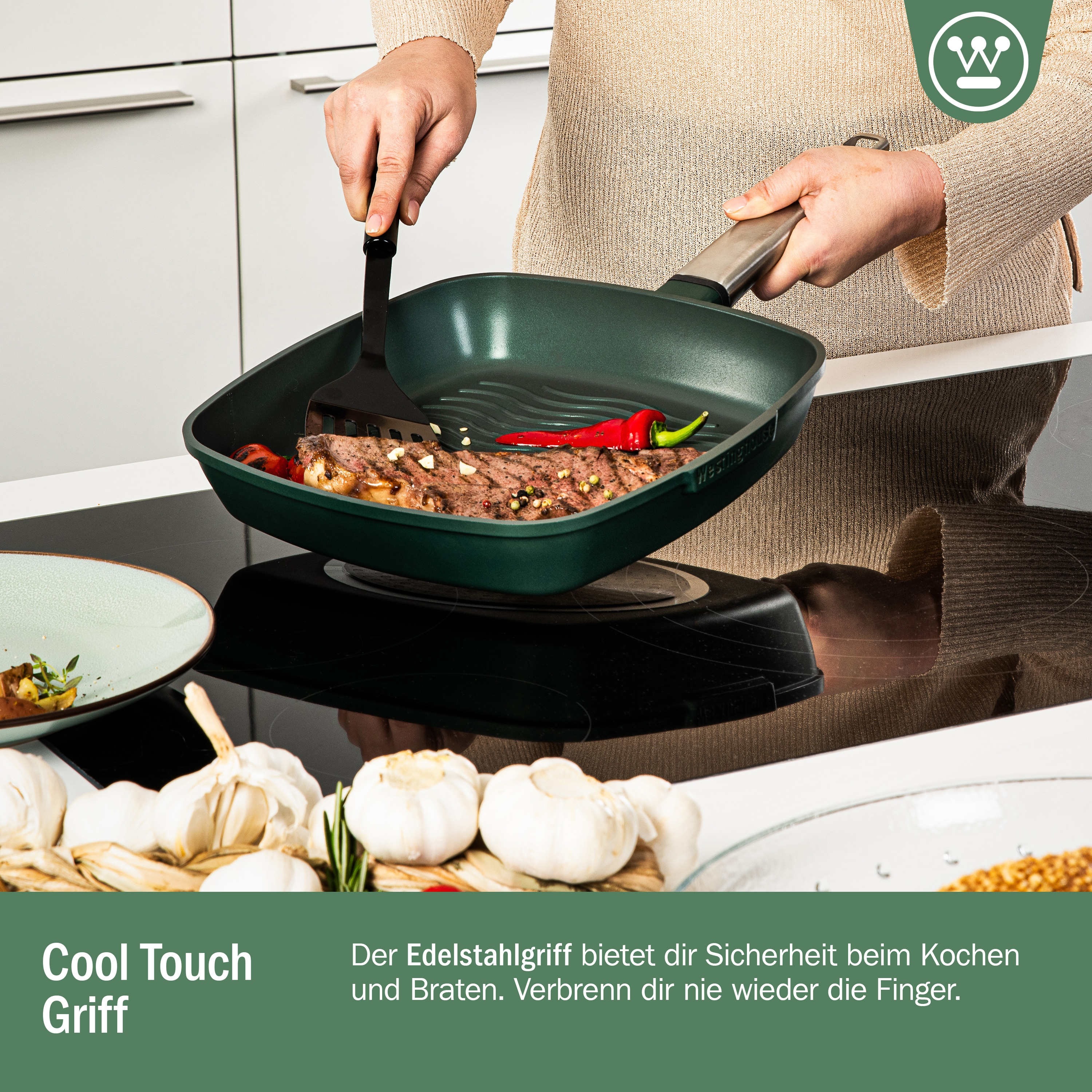 Person kocht Fleisch in einer grünen Pfanne. Gemüse und Knoblauch liegen auf der Theke.