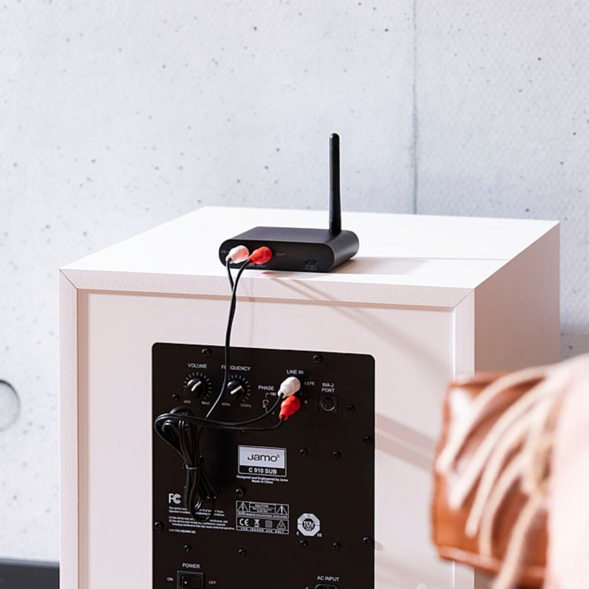 Récepteur audio noir avec des haut-parleurs blancs, connecté par des câbles rouges et blancs.