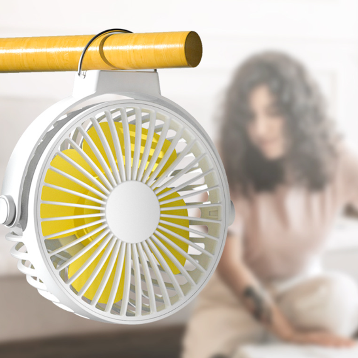 Weiß-gelber Ventilator, der an einer Holzstange hängt. Eine verschwommene Frau ist im Hintergrund.