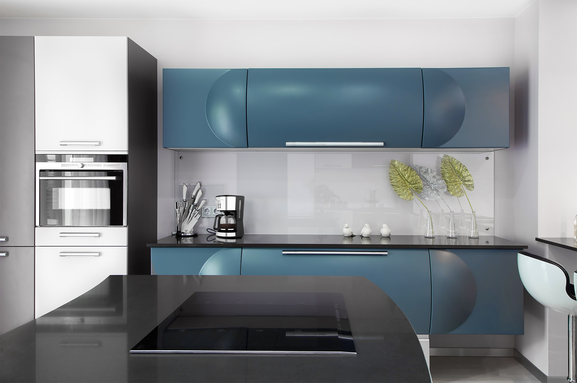 Nowoczesna kuchnia z niebieskimi szafkami i czarnym blatem.