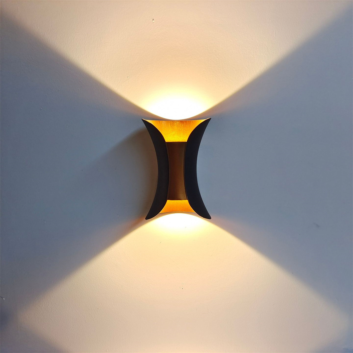 Moderne Wandlampe, die Licht gegen eine hellfarbige Wand ausstrahlt.