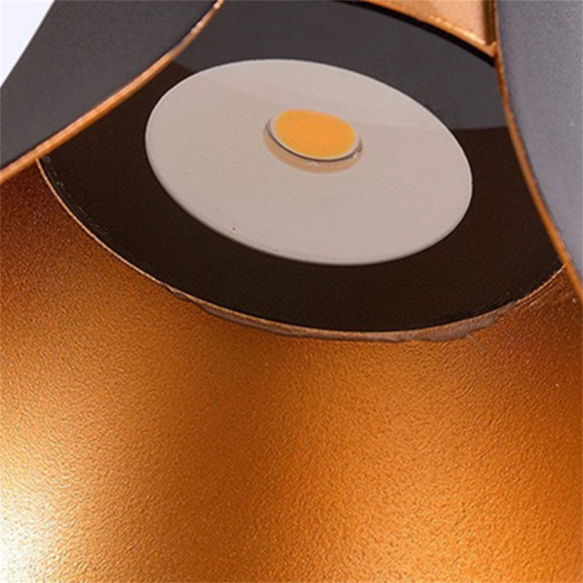 Nahaufnahme eines metallisch goldenen Lampenschirms mit weißer Lichtquelle.