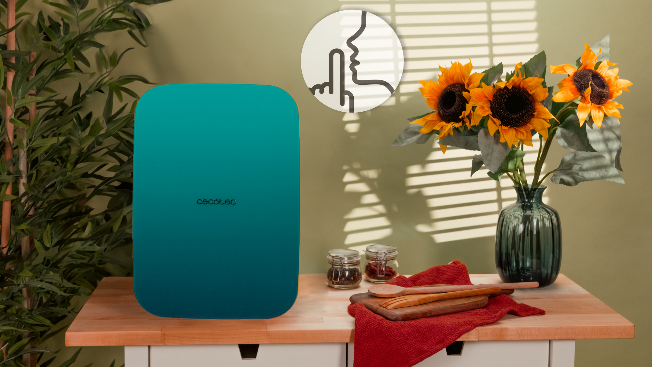 Una mesa con un purificador de aire azul-verde, girasoles y artículos de cocina.