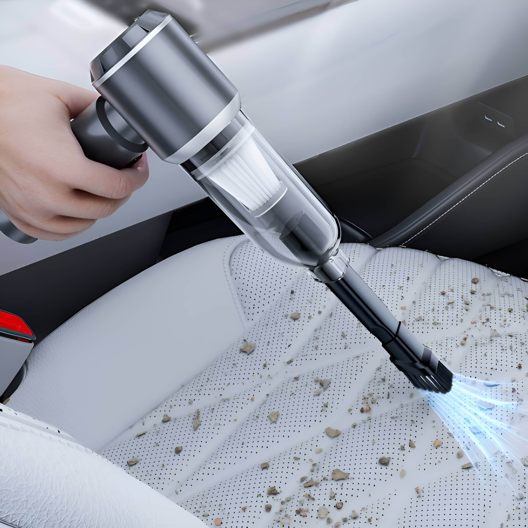Hand, die einen Staubsauger auf einem Autositz verwendet. Der Staubsauger ist klein und grau.