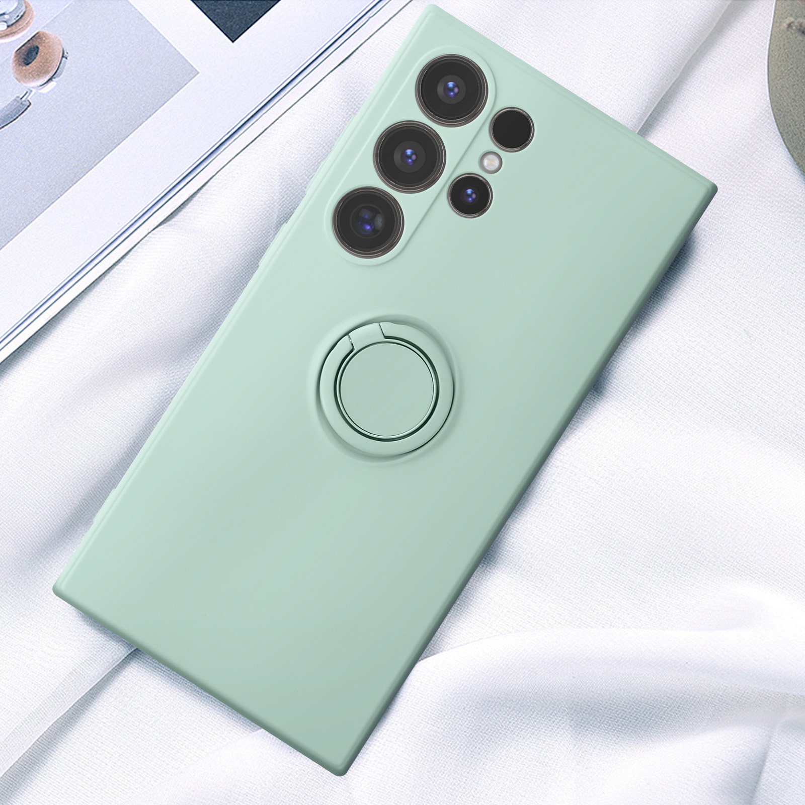 Una custodia per telefono verde menta con un supporto ad anello circolare su un panno bianco.
