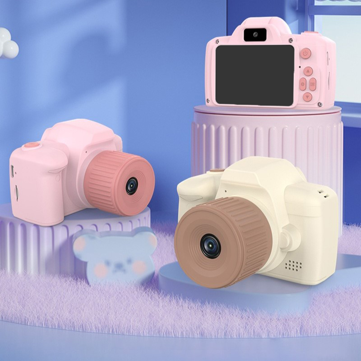 Drei rosa und cremefarbene Kameras stehen auf einer blauen Oberfläche. Ein bärenförmiges Objekt ist zu sehen.