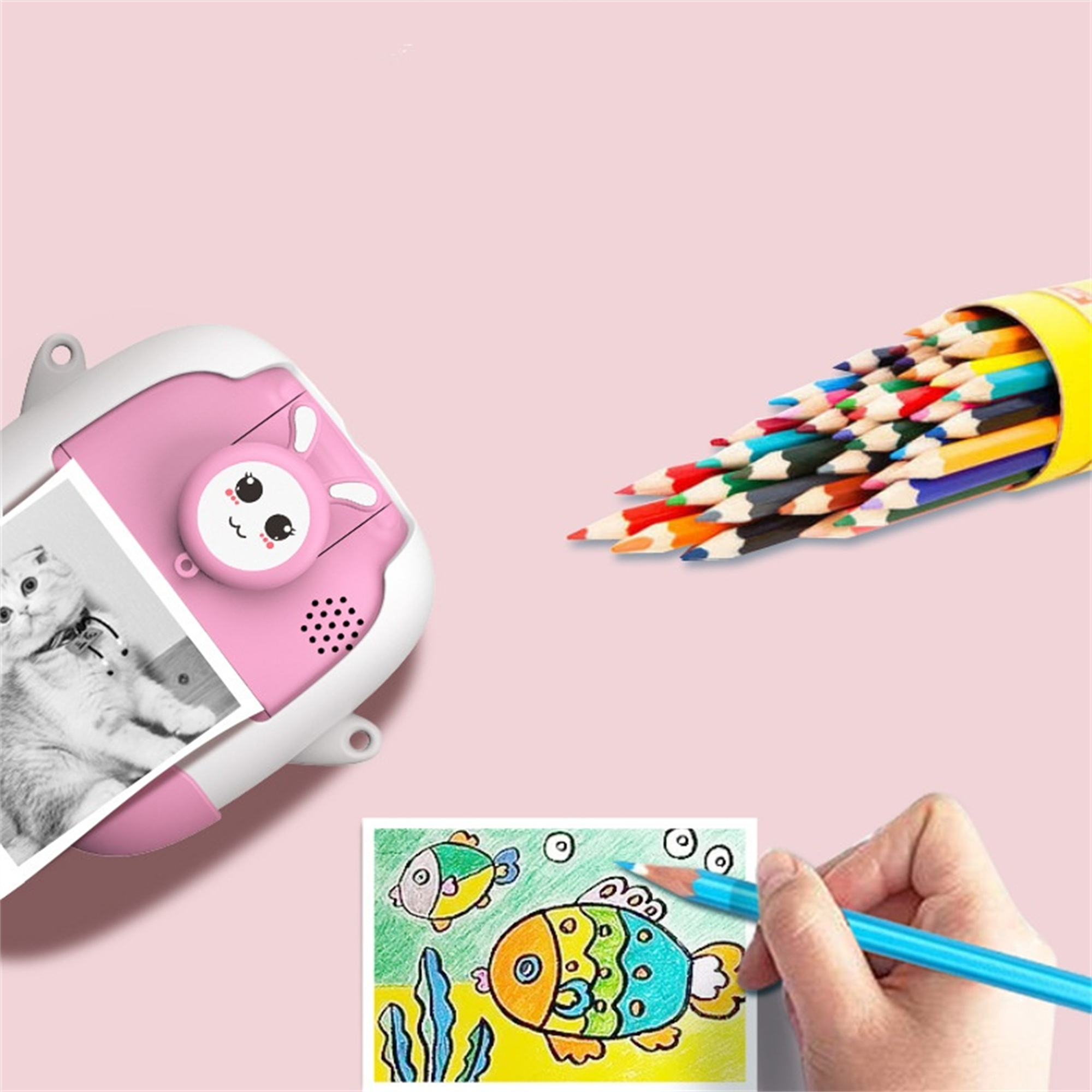 Rosa kameraförmiges Spielzeug, Bleistifte und eine Zeichnung von Fischen. Rosa Hintergrund.