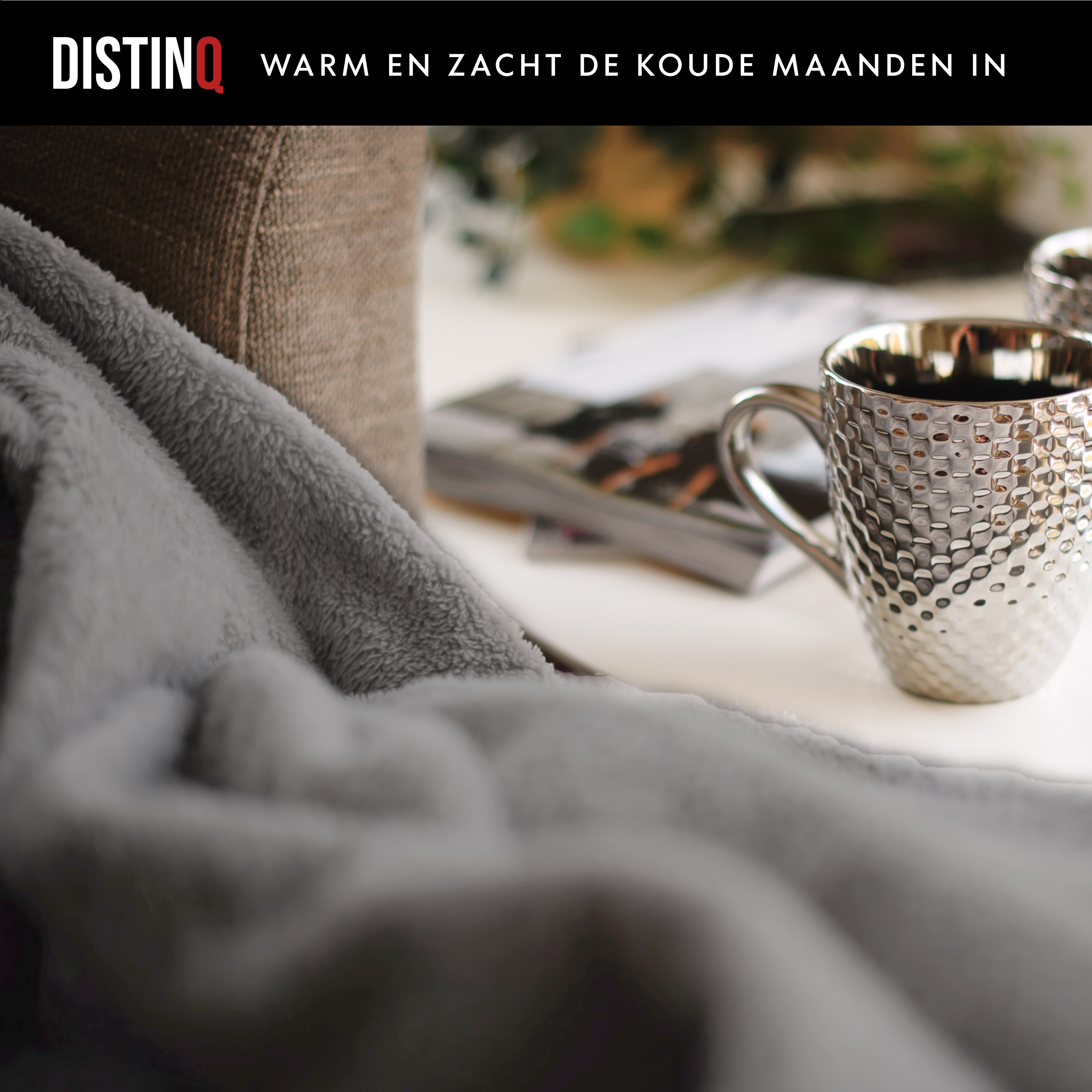 A cozy scene with a blanket, mug, and book. Text on the top DistinQ: Warm in the cold months.